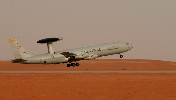 An E-3 Senty AWACS takes off in the desert.