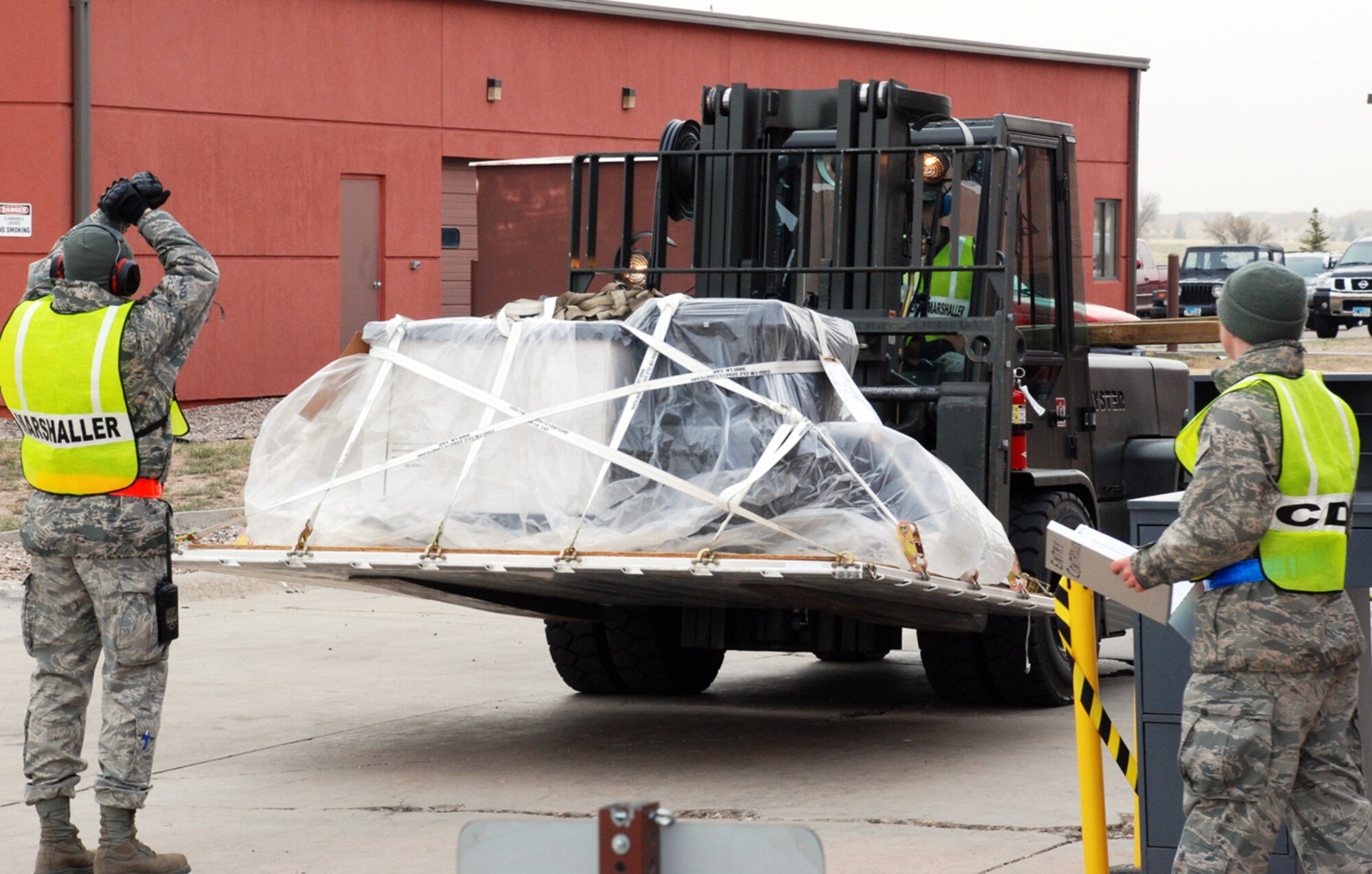 Airman Colwell motions the forklift to stop, while Airman 1st Class Ricky Sherman, 90th LRS, prepares to inprocess the cargo. The in checking area is used to check the pallet's height, weight, netting and paperwork to ensure the cargo is ready for shipment. If there are any problems with the pallet, it could be delayed, and it will have to be fixed before it is processed and ready for transport.