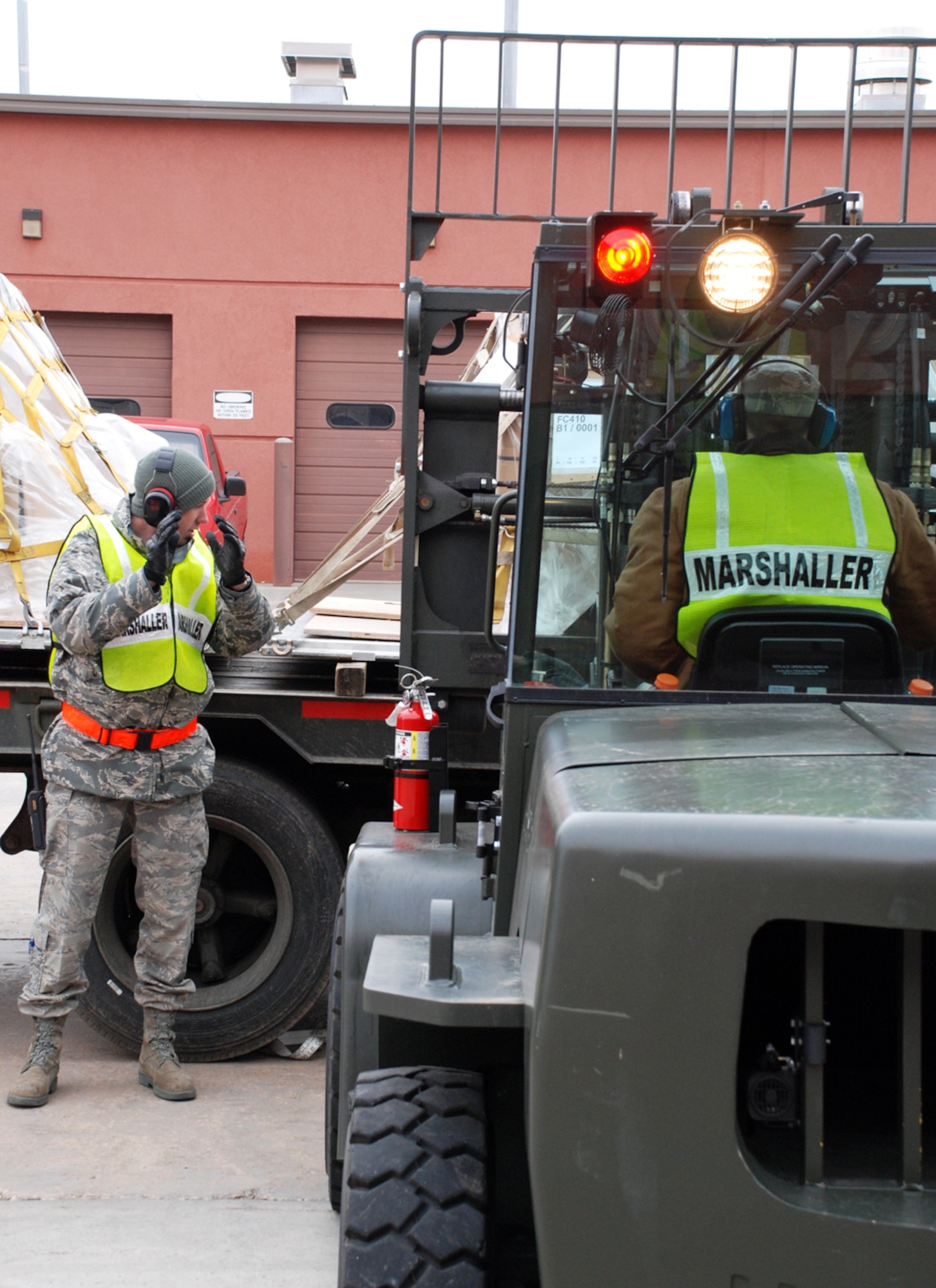 Airman 1st Class Justin Colwell, 90th Logistics Readiness Squadron, helps marshall the forklift driver Airman 1st Class Cody Jones, 90th LRS, toward the truck to unload the cargo pallets April 30 during the Phase I exercise at Bldg. 1284.