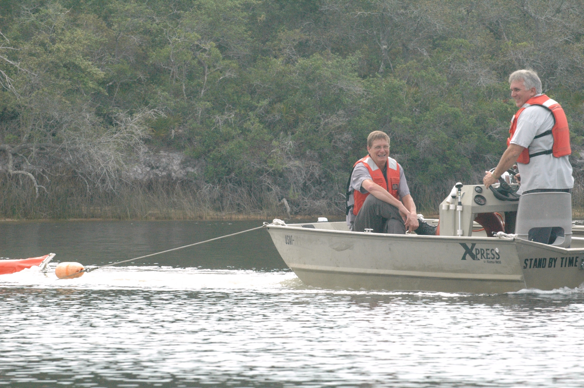 (Left in boat) Tim Tolle and Chris Linder of Del-Jen, Inc., lead an oil spill containment boom back to the shore of Fred Bayou May 12 at Tyndall Air Force Base, Fla. Bringing the boom in signaled the ending of a nearly four-hour exercise to simulate a worst-case scenario oil discharge occuring as the result of a natural disaster. Several base agencies were involved to accomplish the exercise objectives. (U.S. Air Force photo/Staff Sgt. Joshua Stevens)