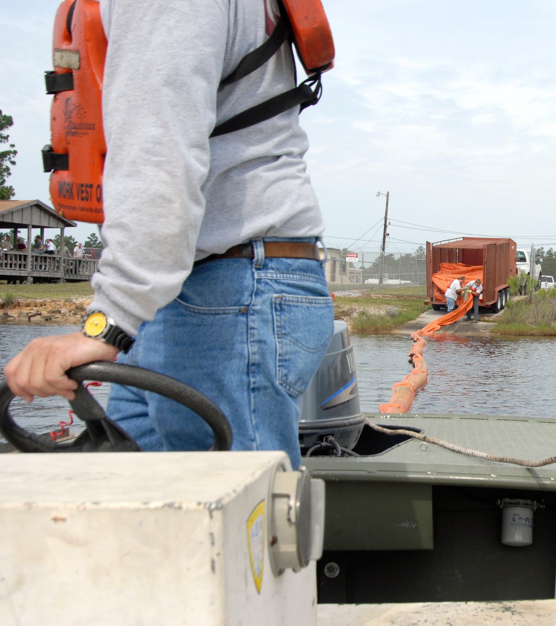 A contracted worker for Southern Waste Services, Inc., out of Panama City, Fla., gazes behind his boat May 12 in Fred Bayou at Tyndall Air Force Base, Fla., to make sure an oil spill containment boom is properly  stretched across the length of the bayou. The boom was utilized to simulate actual procedures which would be taken should a worst-case discharge scenario occur as the result of a natural disaster. Several base agencies worked together to accomplish the exercise. (U.S. Air Force photo/Robin Walters)