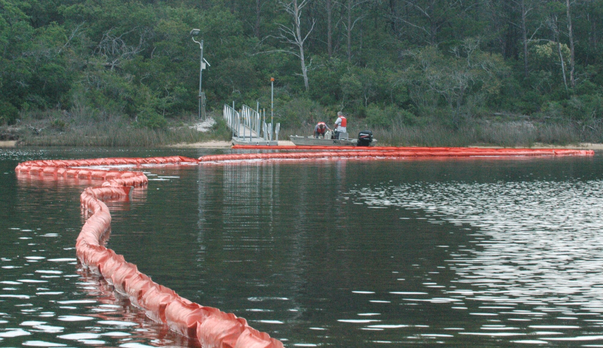 An oil spill containment boom is stretched across Fred Bayou by Tim Tolle and Chris Linder of Del-Jen, Inc., May 12 at Tyndall Air Force Base, Fla. The boom was utilized to simulate actual procedures which would be taken should a worst-case discharge scenario occur as the result of a natural disaster. Several base agencies worked together to accomplish the exercise. (U.S. Air Force photo/Staff Sgt. Joshua Stevens)