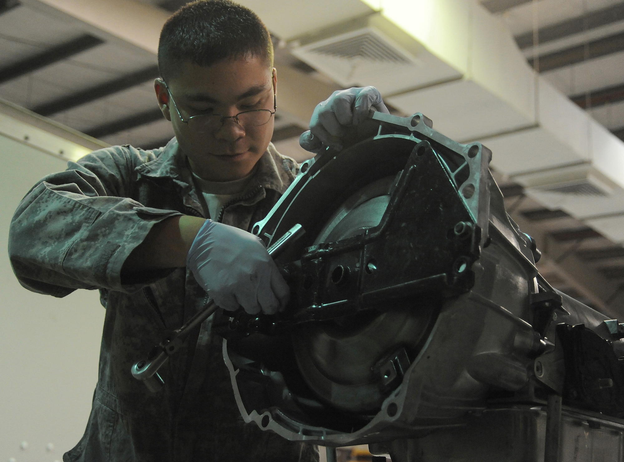Senior Airman Michael Jakubec takes off a torque converter shield from a transmission April 26 at an air base in Southwest Asia. The shield is placed on the transmission to protect the torque converter during shipping. Airman Jakubec is a 380th Expeditionary Logistics Readiness Squadron vehicle maintainer deployed from Kadena Air Base, Japan. He is from Spanaway Wash. (U.S. Air Force photo/Senior Airman Brian J. Ellis)