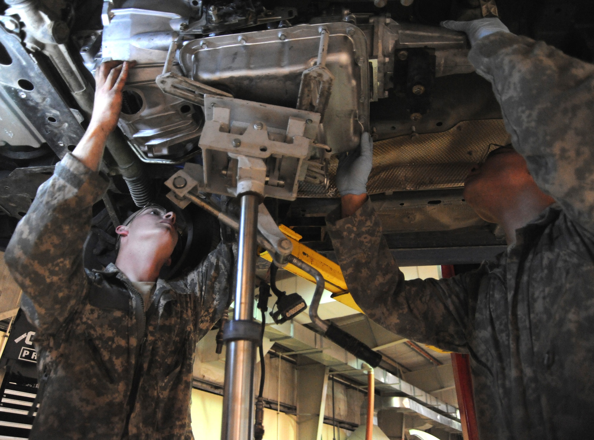 Senior Airman Adam Owens and Senior Airman Michael Jakubec raise up a new transmission into a Pontiac GTO April 26 at an air base in Southwest Asia. The GTO is used as a chase car to help guide U-2 pilots during takeoffs and landings. Airmen Owens and Jakubec are 380th Expeditionary Logistics Readiness Squadron vehicle maintenainers. Airman Owens is deployed from the 174th Air National Guard Base from Hancock Field, N.Y. Airman Jakubec is deployed from Kadena Air Base, Japan. (U.S. Air Force photo/Senior Airman Brian J. Ellis) 