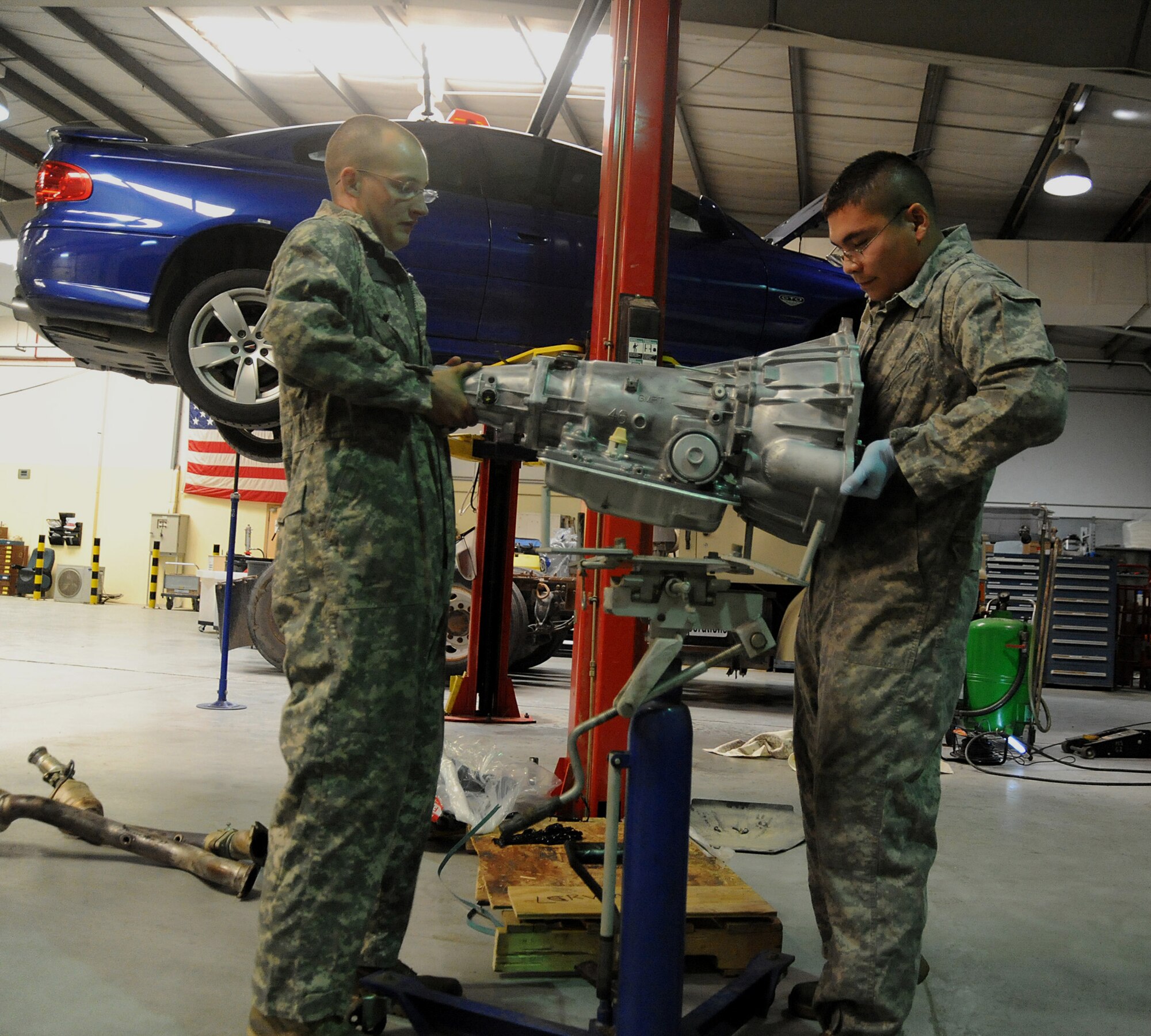 Senior Airman Adam Owens and Senior Airman Michael Jakubec lift a transmission onto a transmission jack so it can be raised into a Pontiac GTO April 26 at an air base in Southwest Asia. The GTO is used as a chase car to help guide U-2 pilots during takeoffs and landings. Airman Owens is deployed from the 174th Air National Guard Base at Hancock Field, N.Y. Airman Jakubec is deployed from Kadena Air Base, Japan. Airmen Owens and Jakubec are 380th Expeditionary Logistics Readiness Squadronvehicle maintainers. (U.S. Air Force photo/Senior Airman Brian J. Ellis) 

