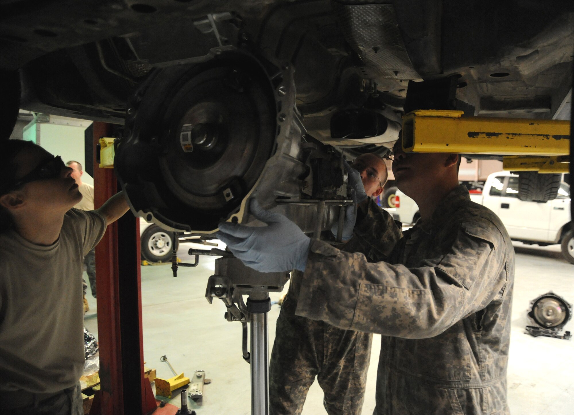 Lt. Col. Tanya Kubinec, Senior Airman Adam Owens and Senior Airman Michael Jakubec line up a new transmission with the engine of a Pontiac GTO April 26 at an air base in Southwest Asia. Colonel Kubinec, the 380th Expeditionary Logistics Readiness Squadron commander, coined the two Airmen for their work on the GTO as well as other critical vehicles belonging to the 380th Air Expeditionary Wing. Airmen Owens and Jakubec are 380th ELRS, vehicle maintainers. (U.S. Air Force photo/Senior Airman Brian J. Ellis)