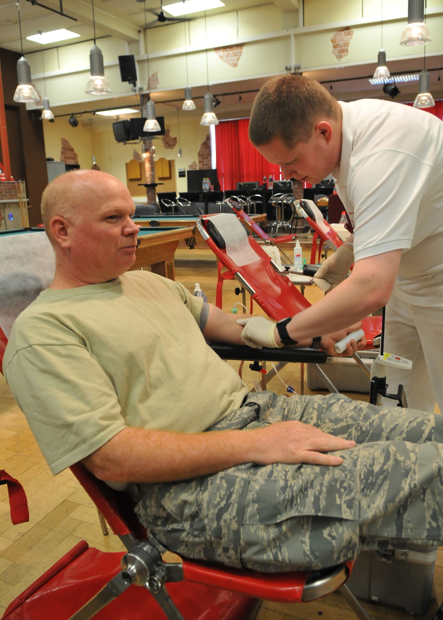SPANGDAHLEM AIR BASE, Germany – Chief Master Sgt. Mark Booth, 52nd Medical Group superintendant, donates blood as Andreas Niebuhr, German Red Cross Paramedic, prepares him for the procedure May 7, 2009. Sabers, both American and Germans, came together at the Brick House to donate blood. (U.S. Air Force photo by Airman 1st Class Nicholas Wilson)