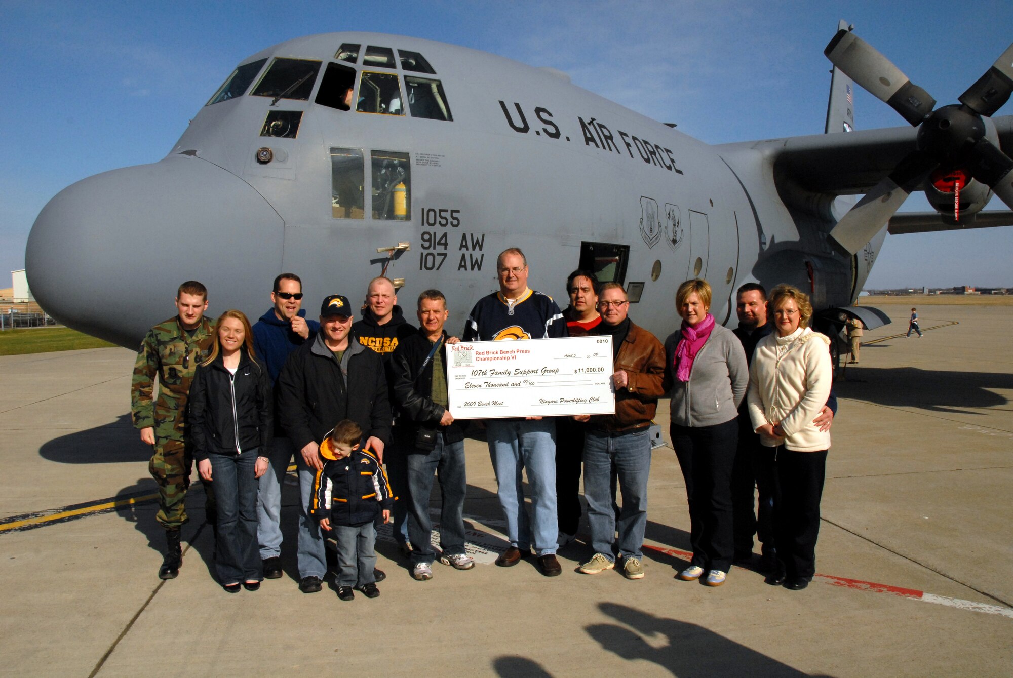 Dennis Brochey (on left) representing the Red Brick Powerlifting Club, presents Col. Timothy Vaughan (in center) and Col. James Atkinson on right with a check for $11,000. The proceeds will be used to benefit deployed Airmen and their families. 
