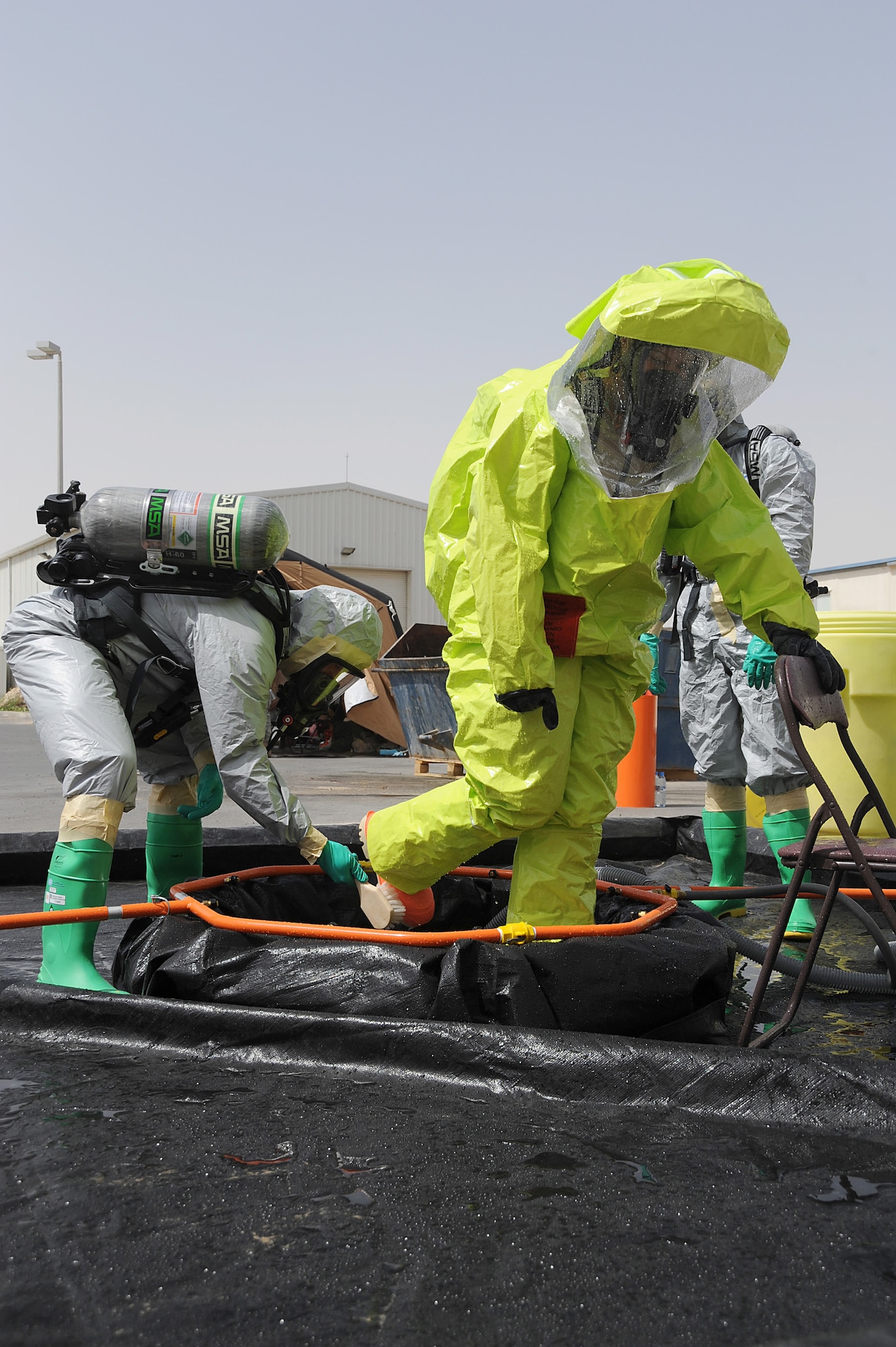 Master Sgt. Jason Golden scrubs the boots of Senior Airman Danielle Clements for contaminants as part of a decontamination area during hazmat decontamination training, May 2 at an undisclosed location in Southwest Asia. They are both deployed with the 380th Expeditionary Civil Engineer Squadron Readiness and Emergency Management Flight. The flight performs Chemical, Biological, Radiological, and Nuclear (CBRN) detection and decontamination operations as well as emergency management command and control. (U.S. Air Force photo by Senior Airman Brian J. Ellis) (Released)
