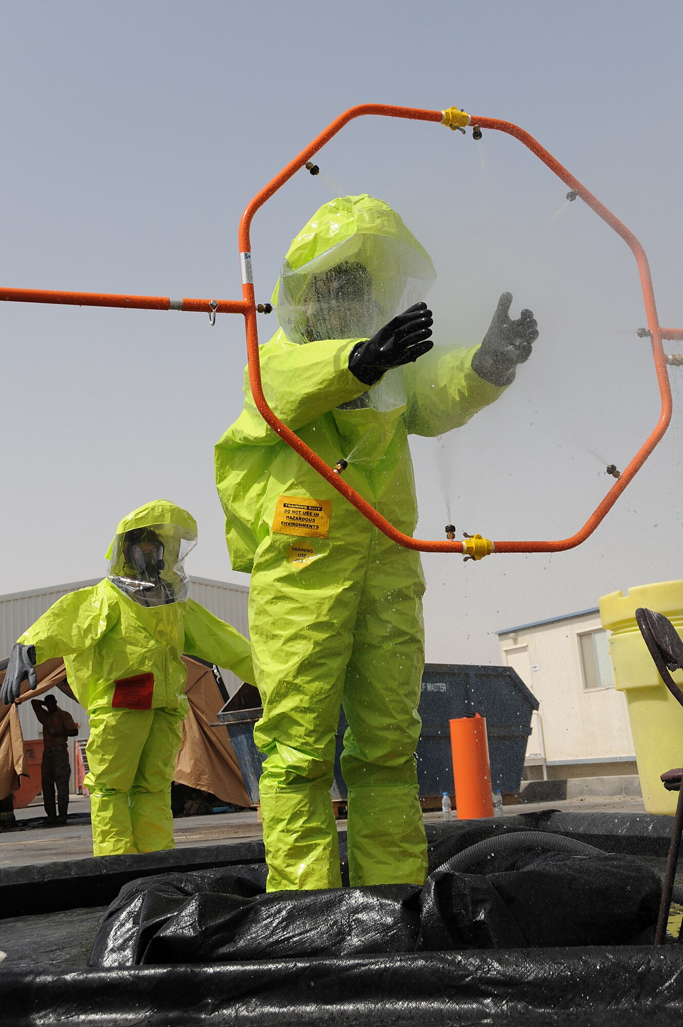 Senior Airman Bradley Cook processes through a decontamination area while Senior Airman Danielle Clements waits during hazmat decontamination training, May 2 at an undisclosed location in Southwest Asia. The Airmen are with the 380th Expeditionary Civil Engineer Squadron Readiness and Emergency Management Flight. The flight performs Chemical, Biological, Radiological, and Nuclear (CBRN) detection and decontamination operations as well as emergency management command and control. (U.S. Air Force photo by Senior Airman Brian J. Ellis) (Released)