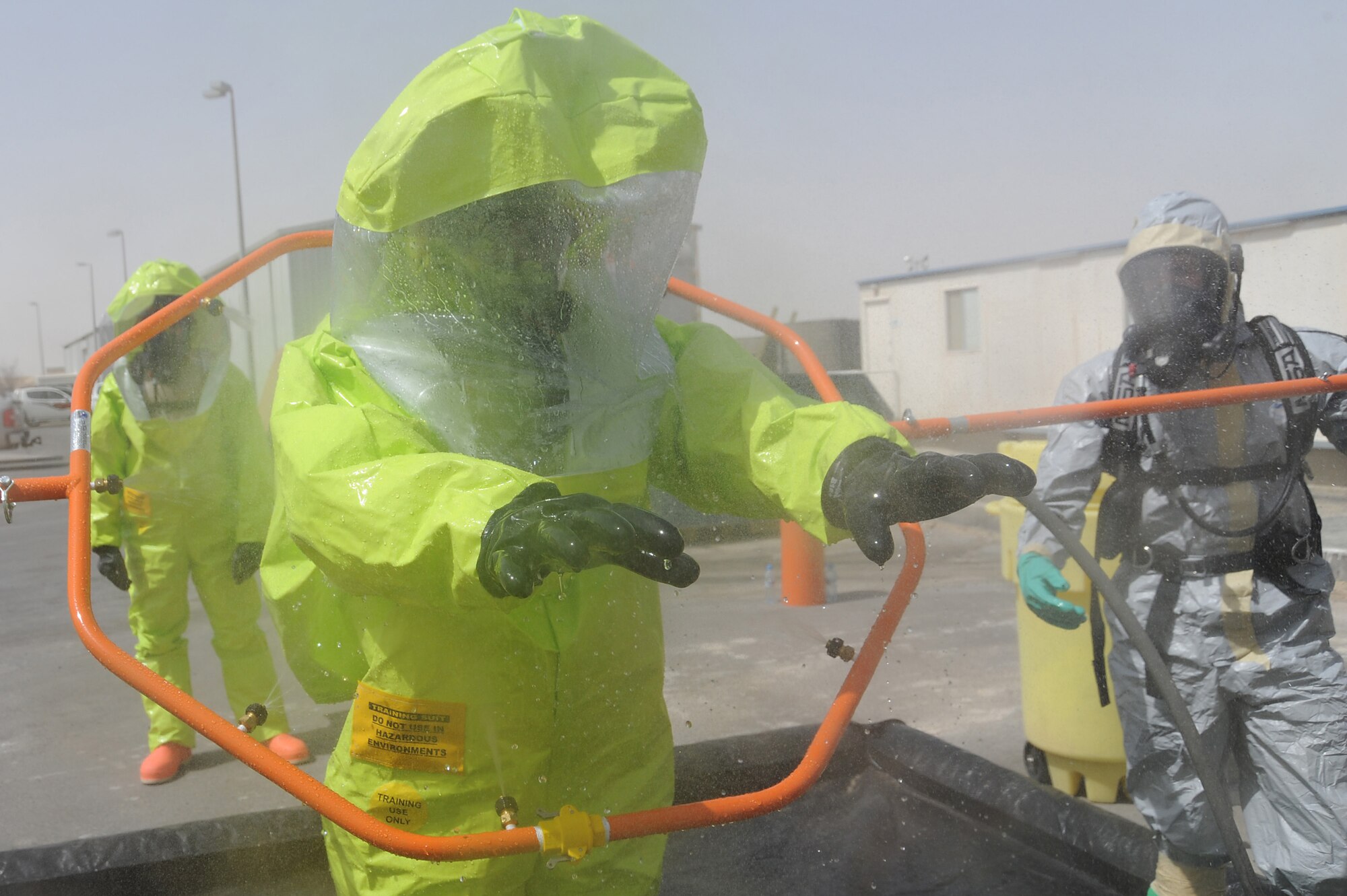Staff Sgt. Demetrius Thompson, 380th Expeditionary Civil engineer Squadron, processes through a hazmat decontamination area while Staff Sgt. Bobo, 380 ECES,  washes off any contaminants from his level-A hazmat suit during hazmat decontamination training, May 2 at an undisclosed location in Southwest Asia. The 380th ECES Readiness and Emergency Management Flight performs Chemical, Biological, Radiological, and Nuclear (CBRN) detection and decontamination operations as well as emergency management command and control. Sergeant Thompson is deployed from Patrick AFB, Fla. and hails from Clinton, MD. Sergeant Bobo is deployed from Aviano AB, Italy and hails from Athens, Ohio. (U.S. Air Force photo by Senior Airman Brian J. Ellis) (Released)