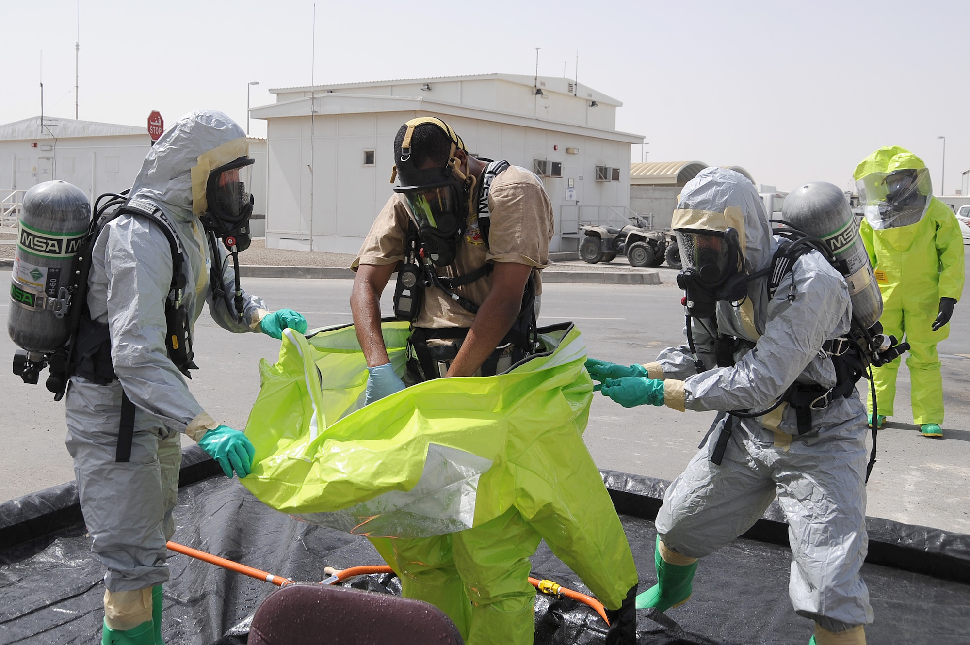 Staff Sgt. Jontae Wallace is assisted out of a Level-A hazmat suit by Master Sgt. Jason Golden and Staff Sgt. Bobo during hazmat decontamination training, May 2 at an undisclosed location in Southwest Asia. All three Airmen are with the 380th Expeditionary Civil Engineer Squadron Readiness and Emergency Management Flight. The flight performs Chemical, Biological, Radiological, and Nuclear (CBRN) detection and decontamination operations as well as emergency management command and control. (U.S. Air Force photo by Senior Airman Brian J. Ellis) (Released)