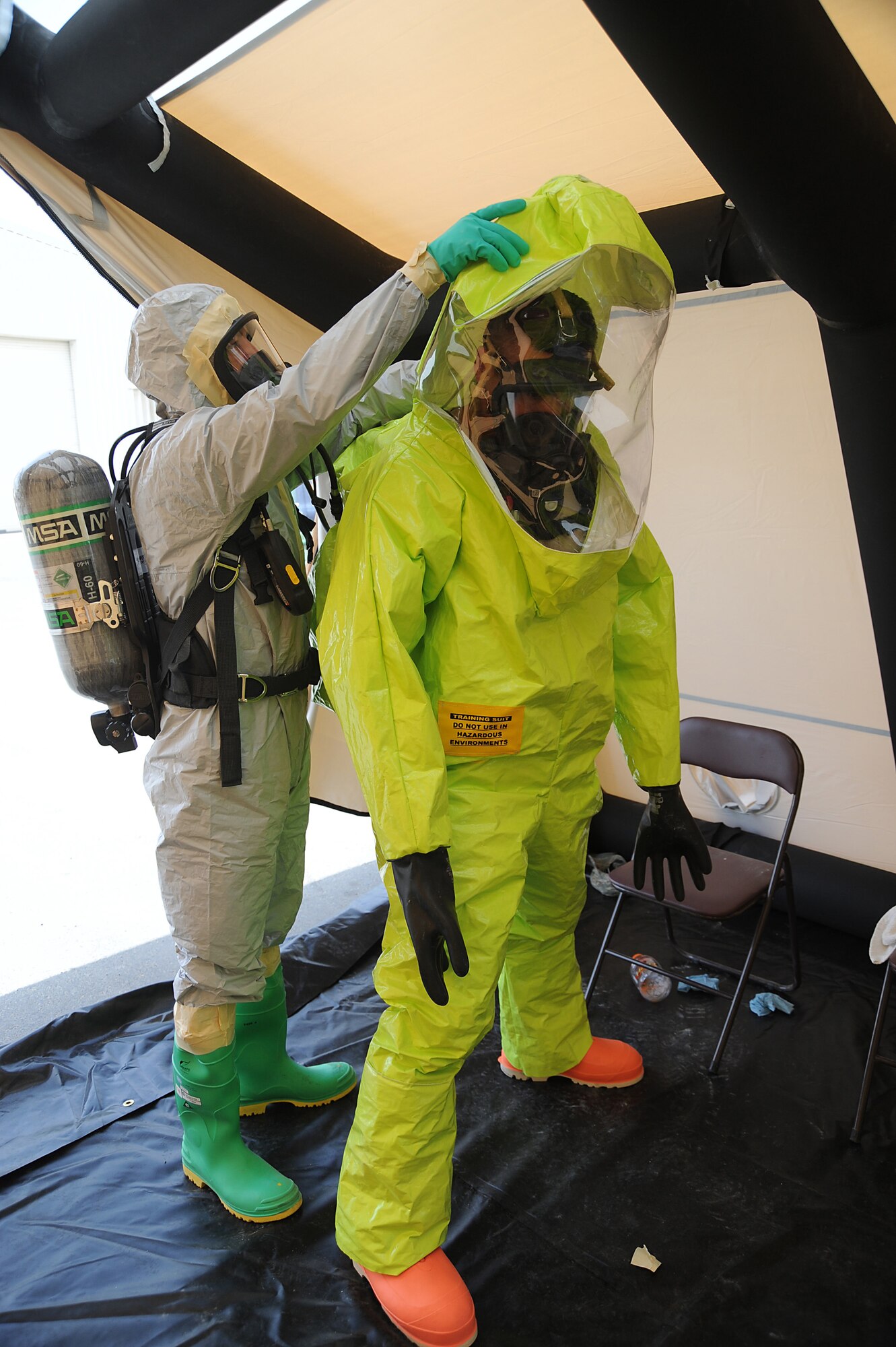 Master Sgt. Jason Golden, 380th Expeditionary Civil Engineer Squadron, assists Senior Airman Bradley Cook, 380th ECES, with sealing off his level-A hazmat suit, May 2 at an undisclosed location in Southwest Asia. The 380th ECES Readiness and Emergency Management Flight, conducted hazmat decontamination training to keep their proficiency skills sharp and ready for real world. Sergeant Golden is deployed from Andres AFB, Md. and hails from Wolf Creek, Mont. Airman Cook is deployed from Andrews AFB, Md. and hails from El Paso, Texas. (U.S. Air Force photo by Senior Airman Brian J. Ellis) (Released)