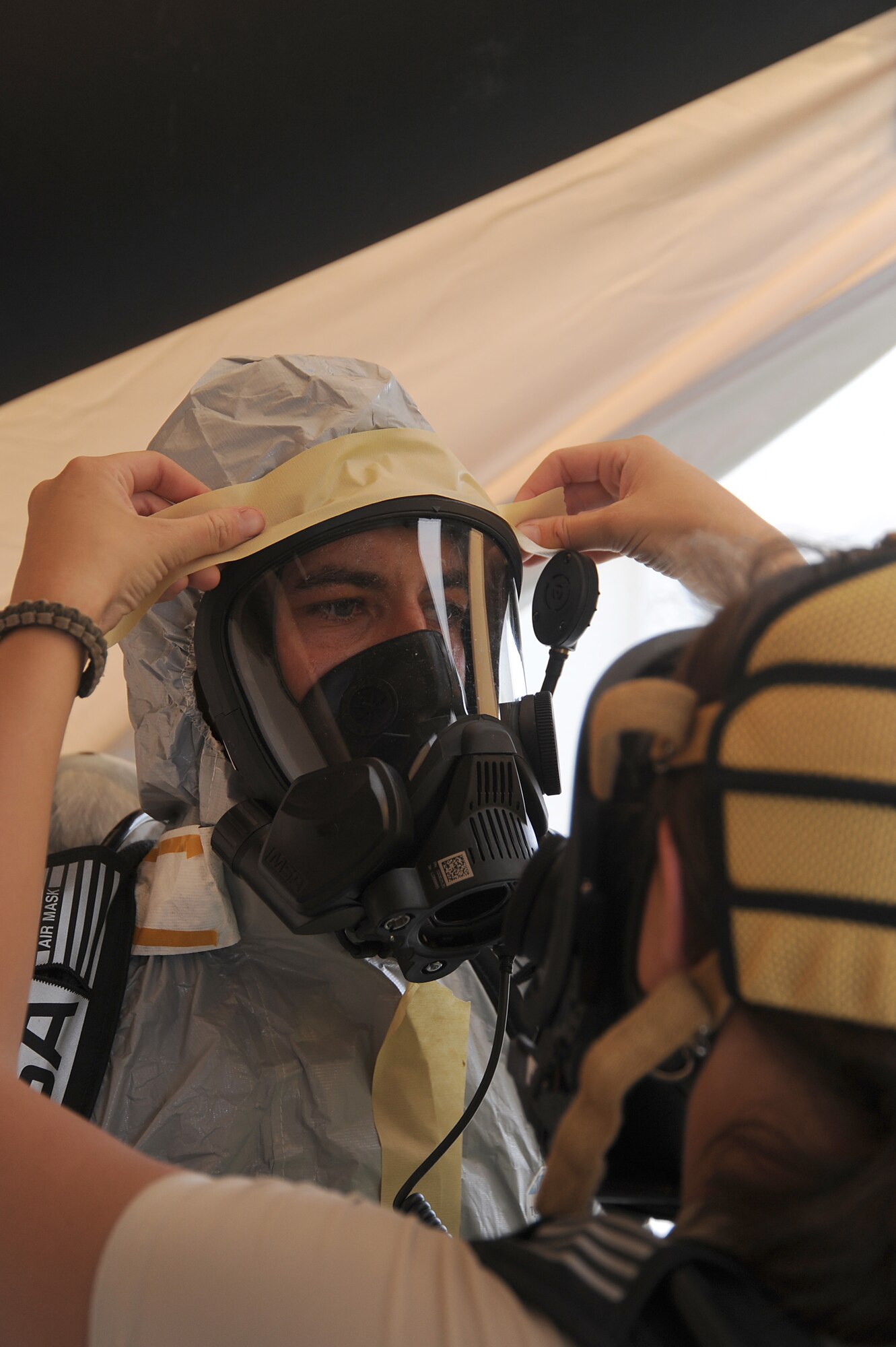 Staff Sgt. Cory Bobo, 380th Expeditionary Civil Engineer Squadron, is assisted with sealing off his level-B Hazmat suit by Senior Airman Danielle Clements, 380th ECES, May 2 at an undisclosed location in Southwest Asia. The 380th ECES Readiness and Emergency Management Flight perform Chemical, Biological, Radiological, and Nuclear (CBRN) detection and decontamination operations as well as emergency management command and control. Sergeant Bobo is deployed from Aviano AB, Italy and hails from Athens, Ohio. Airman Clements is deployed from Andrews AFB, Md. and hails from Augusta, Ga. (U.S. Air Force photo by Senior Airman Brian J. Ellis) (Released)