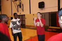 Lance Cpl. Tommy G. Roque, 19 from Dunkirk, N.Y., instructs students from Proviso West High School on a proper defensive posture during Marine Week Chicago. Roque taught the children different defensive techniques like catching, slipping and rolling punches. Two other member of the boxing team attended the visit and showed the students offensive techniques and boxing exercises.