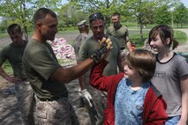 Sgt Jeremy Owens, left, 3rd Assault Amphibian Battalion, 1st Marine Division, gives a local child a 'high five' after completing a small job together at Riis Park in Chicago May 12, 2009. Marines are cleaning up parks as well as taking part in other community services and efforts as part of Marine Week being held in Chicago. (U.S. Marine Corps photo by Cpl. Seth Maggard/Released)