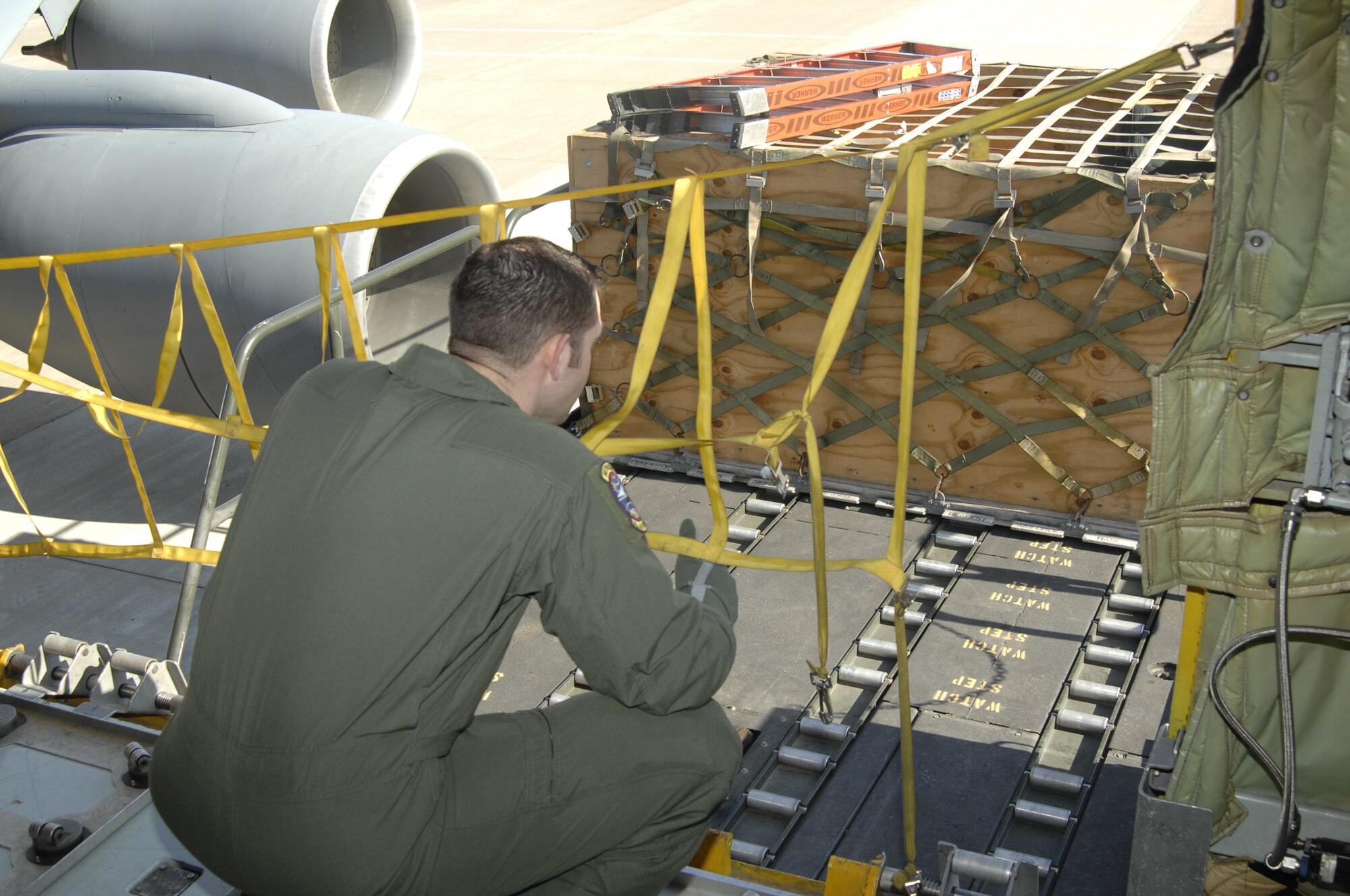 MCCONNELL AIR FORCE BASE, Kan. -- Staff Sgt. Gary Shamlian, 349th Air Refueling Squadron boom operator, guides a 22nd Logistics Readiness Squadron Airman to the proper height a cargo loader needs to get to safely load cargo pallets onto a KC-135 Stratotanker in support of a multi lateral exercise, April 15.  With the help of rotating wheel brackets, cargo can easily be loaded and guided into McConnell aircraft and securely locked in place for transport. (Photo by Staff Sgt. Ronald Lafosse)