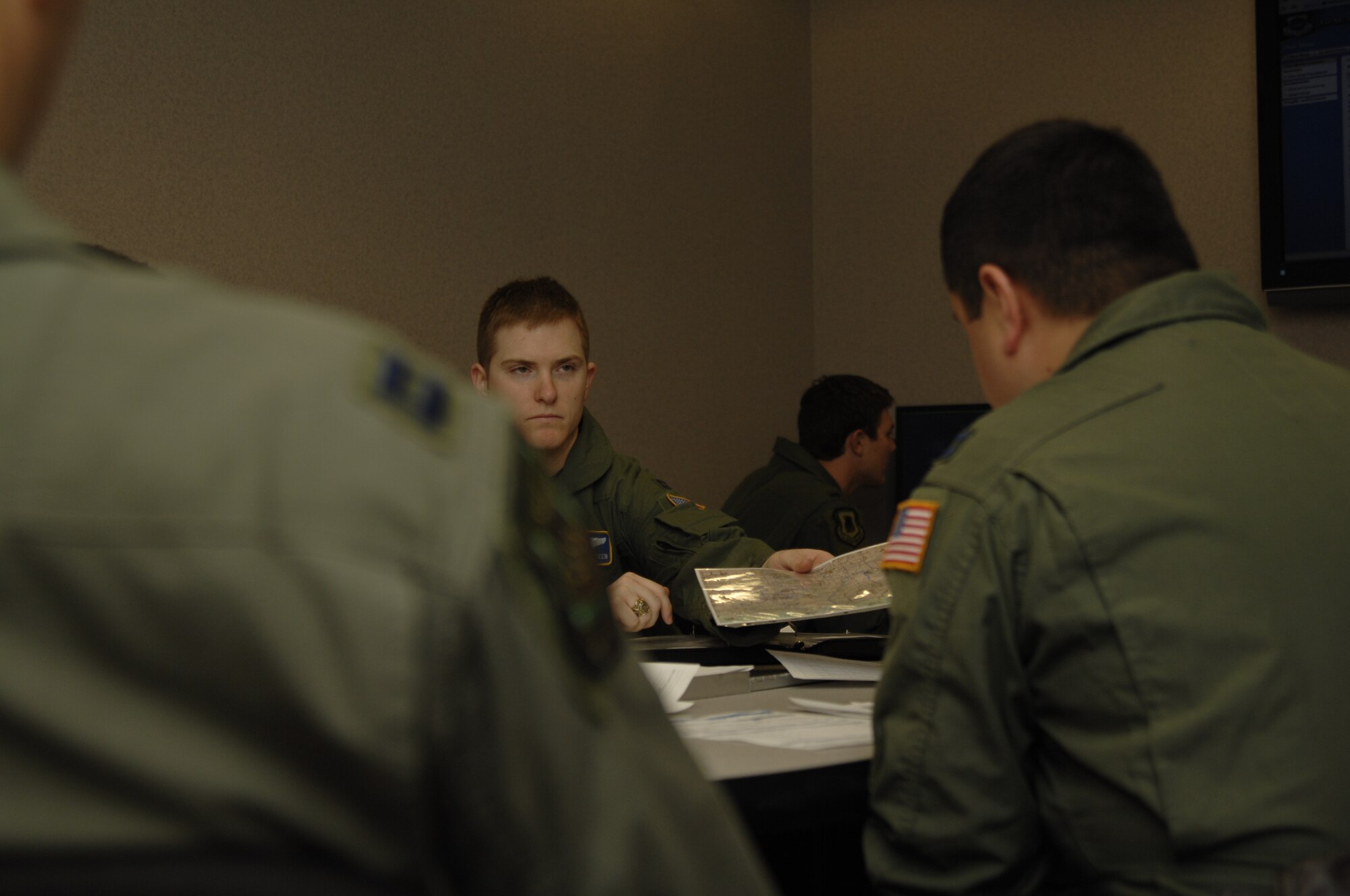 MCCONNELL AIR FORCE BAES, Kan. -- Capt. Brandon O’Steen, a navigator with the 384th Air Refueling Squadron, hands a flight map to Capt. Samuel Dixon, a pilot with the 384th ARS, during a mission crew brief with chalk one flight crews for a multi lateral exercise, April 15. Mission crew briefs are essential to the success of a sortie, exercise or flight.  (Photo by Staff Sgt. Ronald Lafosse)