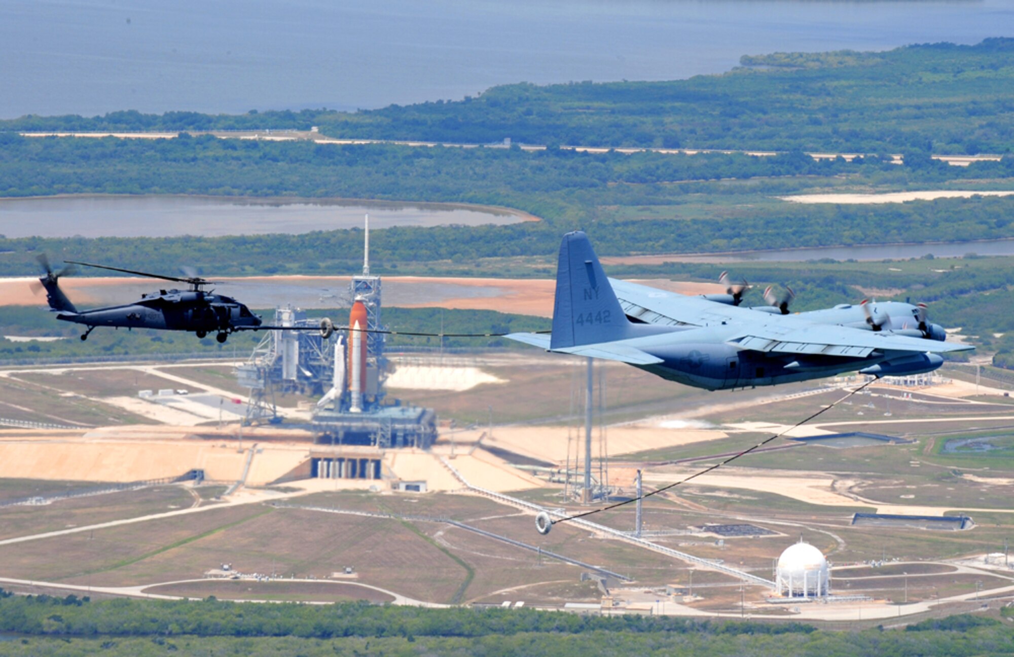 An HH-60G Pave Hawk helicopter from Air Force Reserve Command's 920th Rescue Wing receives an in-flight refueling from a Marine Corps C-130 aircraft. Air Force reservists from the Patrick Air Force Base, Fla., unit provide astronaut emergency rescue and public safety support for all manned space shuttles lifting off from Kennedy Space Center. The total force refueling operation took place after the rescuers cleared a 60-mile stretch of the Atlantic Ocean of ships and boats, if they came too close to the launch hazard area. The Airmen then positioned nearby on an alert status to aid the astronauts if an emergency occurred. (U.S. Air Force photo/Tech. Sgt. Gilian Albro)