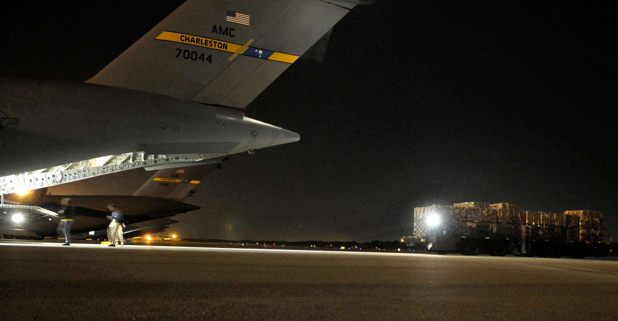 Airman use a 60K loader to transport 30,000 personal protection kits is loaded onto a C-17 Globemaster III at Charleston Air Force Base, S.C., May 8. The personal protection kits were shipped to Haiti, El Salvador, Guatemala, Honduras and Nicaragua. The mission was flown by Airmen from the 437th Airlift Wing at Charleston AFB, with command and control oversight provided by the 618th Tanker Airlift Control Center at Scott AFB, Ill. (U.S. Air Force photo/James M. Bowman) 