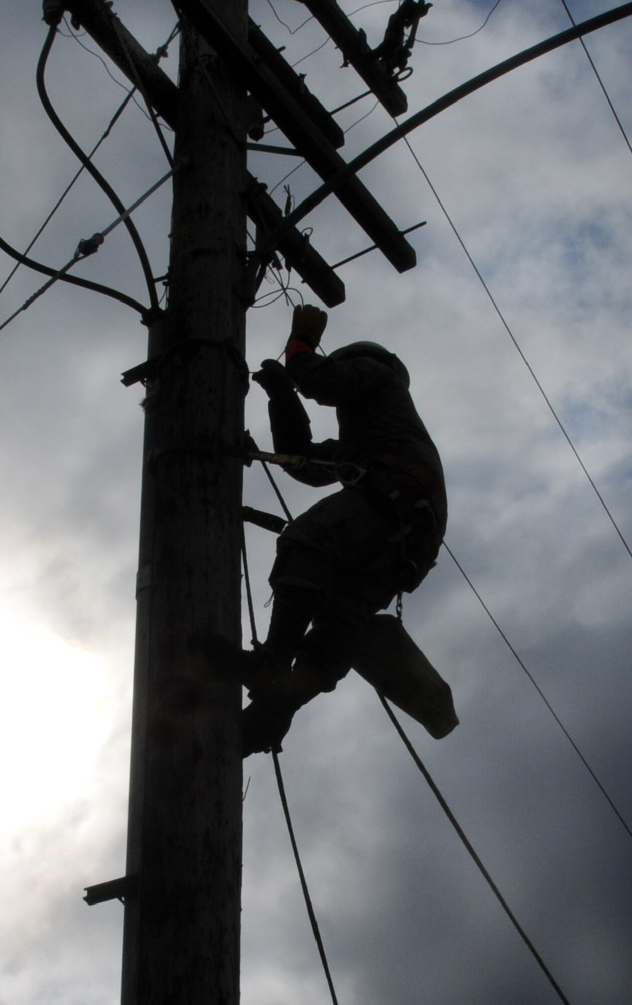 Airman 1st Class Alejandro Velazquez free climbs a utility pole May 12, 2009, Eielson Air Force Base, Alaska. Airman Velazquez prepares the utility pole by removing the fuse cut-outs prior to demolition. The poles are being removed to make a more aesthetically pleasing parking lot. Airman Velazquez is an  Electrical Systems technician with the 354th Civil Engineering Squadron. (U.S. Air Force photo/Airman 1st Class Laura Max)