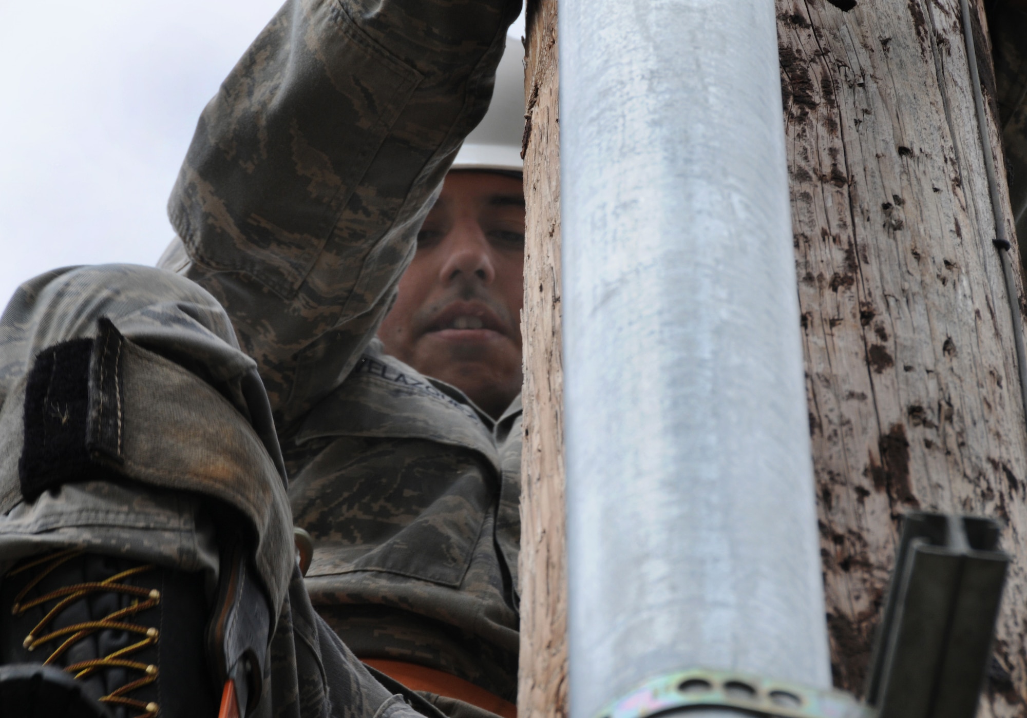 Airman 1st Class Alejandro Velazquez takes a break while free climbing a utility pole May 12, 2009, Eielson Air Force Base, Alaska. Airman Velazquez is climbing the pole to remove fuse cut-outs, one of the many steps taken for safety before demolishing the utility poles to make way for a more aesthetically pleasing parking lot. Airman Velazquez is an Electrical Systems technician with the 354th Civil Engineering Squadron. (U.S. Air Force photo/Airman 1st Class Laura Max)