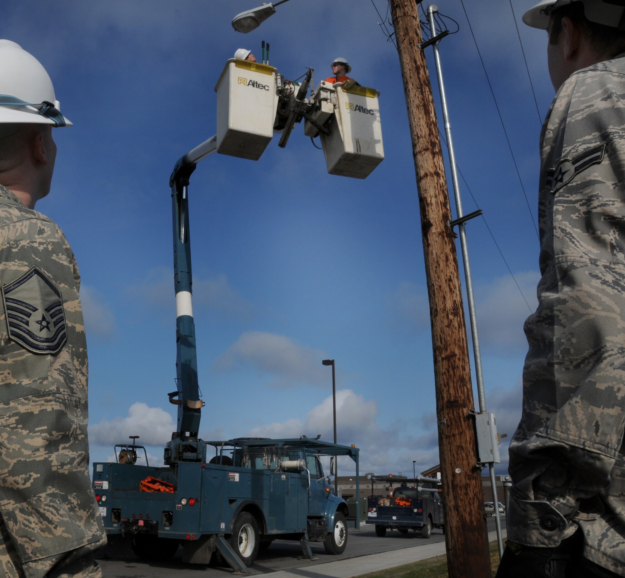Master Sgt. Todd Anderson and Airman 1st Class Alejandro Velazquez look on as Electrical Systems Airmen shut-down the utility pole's power off at the old Burger King facility prior to demolition, May 12, 2009, Eielson Air Force Base, Alaska. The Airmen are with the 354th Civil Engineering Squadron.  (U.S. Air Force photo/Airman 1st Class Laura Max)