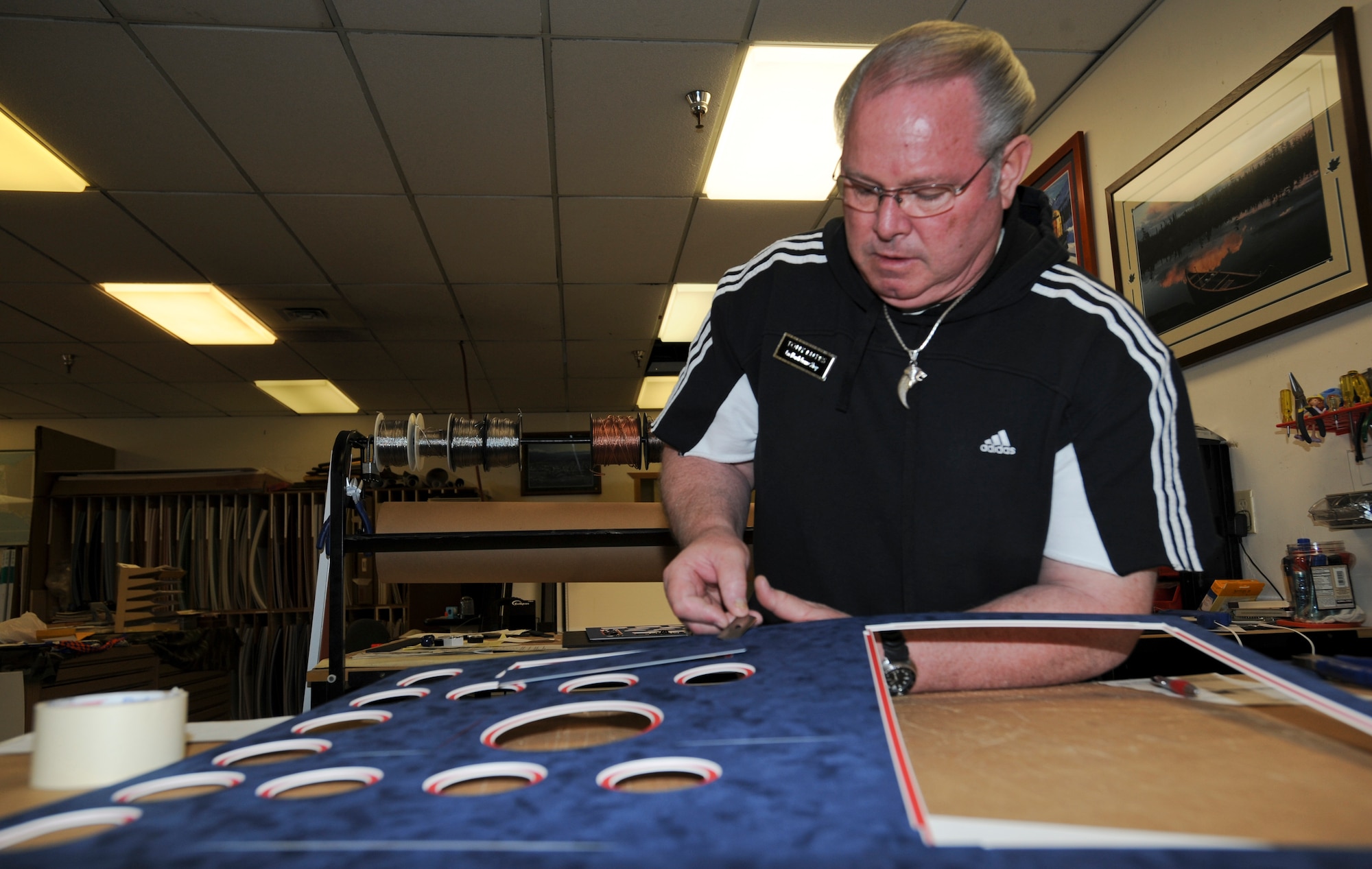 ELMENDORF AIR FORCE BASE, Alaska -- Tony Lutes, 3rd Services Squadron coordinator and retired Air Force maintenance superintendent, cuts out the shapes in the matting for a retirement shadow box at the Arts and Crafts Center, May 5, 2009. The center provides services to military members and their families varying from shadow boxes, plaques, pottery, glass blowing and many more styles of art.(U.S. Air Force photo/Senior Airman Matthew Owens)