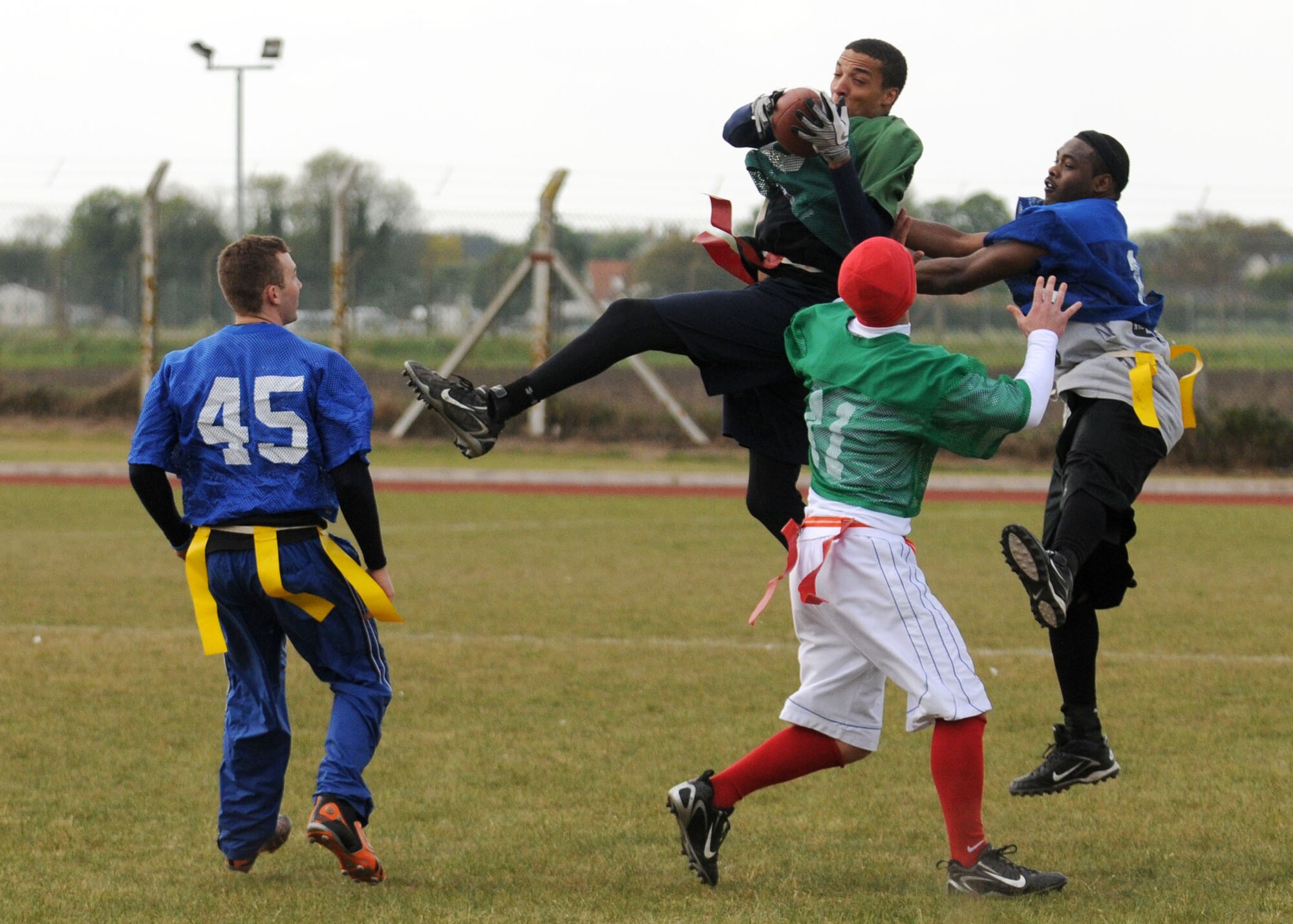 Senior Airman James Dillahunt, 48th Security Forces Squadron, leaps over Senior Airman Chris Murray, 100th Security Forces Squadron, for a 30 yard completion during the flag football game between both security forces squadrons held at Heritage Park May 12, 2009, at RAF Mildenhall, England. The 100th SFS pulled off an easy win over the 48th SFS with a 56-0 victory. The game was held as part of “Police Week” events which pays tribute to all fallen officers across the nation while in the line of duty. (U.S. Air Force photo by Staff Sgt. Jerry Fleshman)
