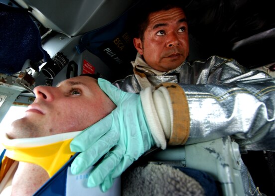 Naoki Iha, 18th Civil Engineer Squadron firefighter, stabilizes a pilot's neck before extracting him from the aircraft to a field treatment team for critical care during Beverly High 09-2 Local Operational Readiness Exercise May 12. The LORE tests base personnel on their combat readiness for real world emergency/combat events. (U.S. Air Force photo/Tech. Sgt. Rey Ramon) 