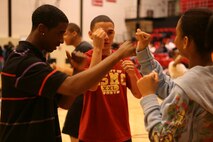 Shaquille Spencer, 16, shadow boxes with Krysten Wilson, 16, in front of the watchful eye of Lance Cpl. Tommy G. Roque, 19. Roque, a boxer on the Marine Corps Boxing Team, and two other Marines from the boxing team visited Proviso West High School during Marine Week Chicago. Marines from various units flocked to Chicago to help the community and display the Marine Corps to the area.