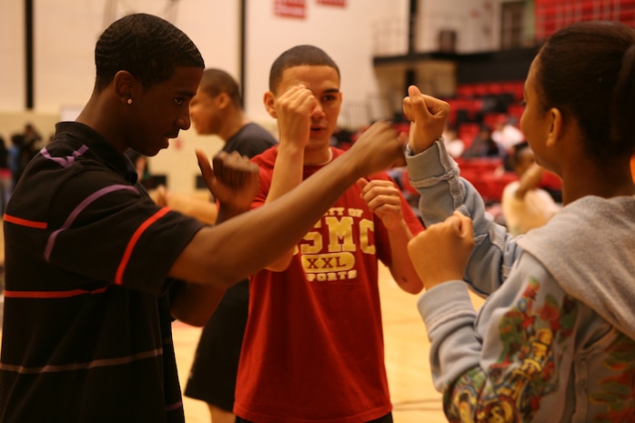 Shaquille Spencer, 16, shadow boxes with Krysten Wilson, 16, in front of the watchful eye of Lance Cpl. Tommy G. Roque, 19. Roque, a boxer on the Marine Corps Boxing Team, and two other Marines from the boxing team visited Proviso West High School during Marine Week Chicago. Marines from various units flocked to Chicago to help the community and display the Marine Corps to the area.