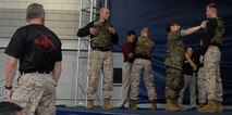 Participants from the crowd are being taught the basic wrist lock, a tan belt level Marine Corps Martial Arts Program technique, during the Martial Arts Center of Excellence demonstration at Soldier Field May 13.