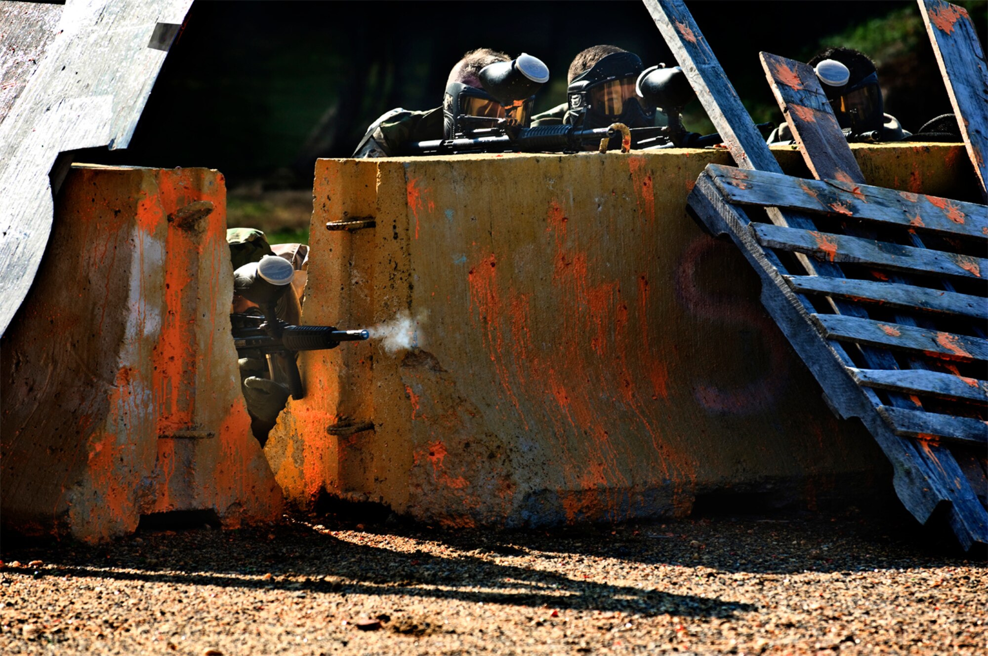 Capt. Maygen Wilson adjusted her lumpy, 5-pound flack vest as she crouched silently behind a large gray concrete pipe. Her wide, thick-lashed blue eyes cautiously scanned for even the slightest movement. A protective full-face mask pressed awkwardly down on her nose, somewhat impeding her vision. She carefully aimed her rifle downrange.
Pop! Pop! Pop! The “bad guys” had initiated their assault. Their weapons? Paintball guns. (photo by Tech. Sgt. Matthew Hannen)