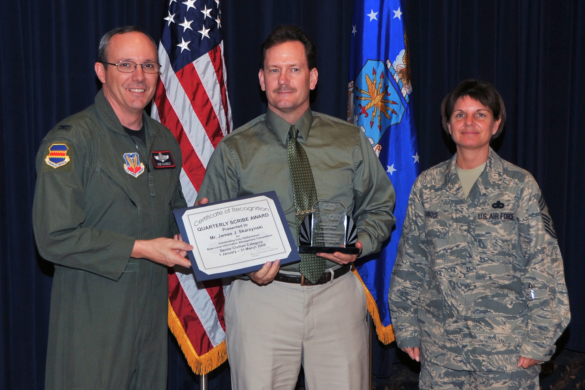 OFFUTT AIR FORCE BASE, Neb. - Col. Robert L. Maness, 55th Wing vice commander, presents James Skarzynski with the Junior Civilian Scribe Award  as 55th Wing Command Chief Master Sgt., Lisa A. Sirois looks on during the Scribe Awards Luncheon at the Patriot Club here May 13. Mr. Skarzynski  earned the honor for outstanding achievement within his career field. Mr. Skarzynski  distinguished himself by ensuring the security for computer and communication equipment valued at $500,000. Air Force Photo by Jeff W. Gates