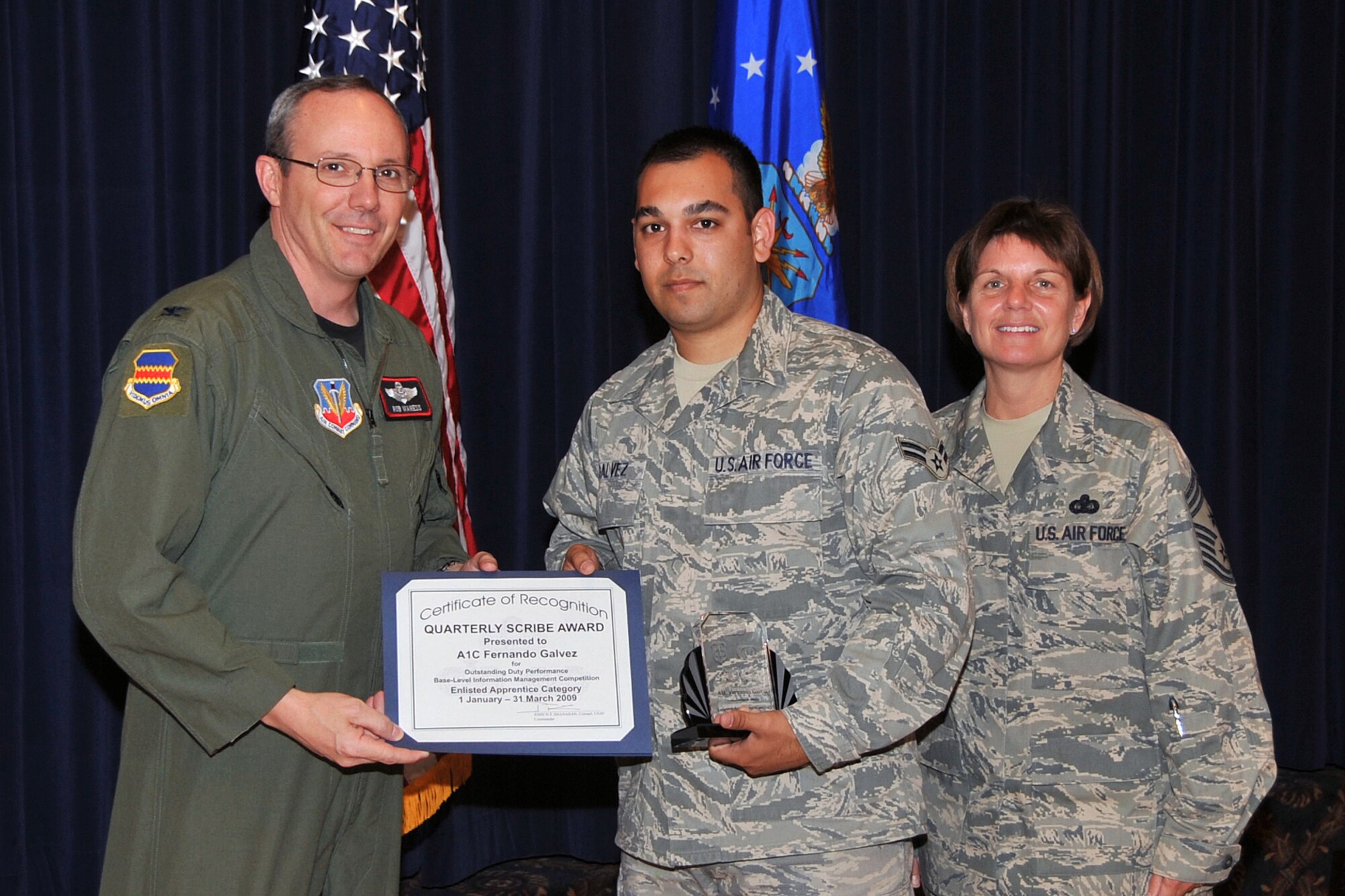 OFFUTT AIR FORCE BASE, Neb. - Col. Robert L. Maness, 55th Wing vice commander, presents Airman 1st Class Fernando Galvez, 55th Maintenance Group, with the Enlisted Apprentice Scribe Award as 55th Wing Command Chief Master Sgt., Lisa A. Sirois looks on during the Scribe Awards Luncheon at the Patriot Club here May 13. Airman Galvez earned the honor for outstanding achievement within his career field. Airman Galvez distinguished himself by training his fellow Airmen and ensuring 16 Operational Readiness Excercise participants had access to necessary computer equipment. Air Force Photo by Jeff W. Gates