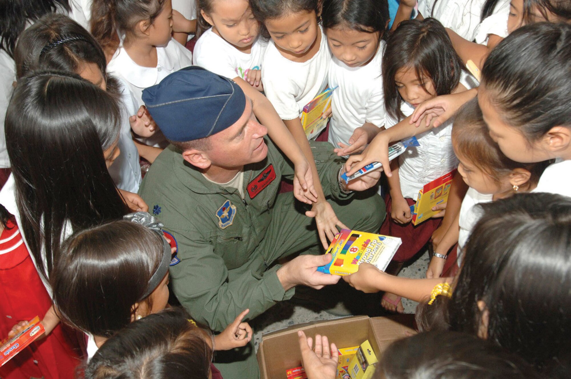 Lt. Col. Jack Maixner, 63rd Fighter Squadron commander, hands out school supplies to Filipino children at the Sapangbato village community center as part of a volunteer community relations event held April 24 and 25 at Angeles City, Philippines.(U.S. Navy photo/ Petty Officer 2nd Class Robert Clowney)