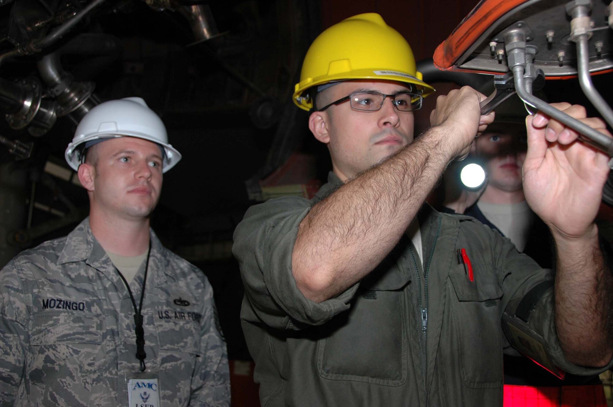 MCGUIRE AIR FORCE BASE, N.J. -- Staff Sgt. Ian Salcedo, center, a Reserve crew chief, tightens a drain line on a KC-10 Extender while Logistics Standardization and Evaluation Program inspector, Technical Sgt. Donald Mozingo watches during the recent LSEP evaluation held here. (U.S. Air Force photo/Master Sgt. Donna T. Jeffries) 