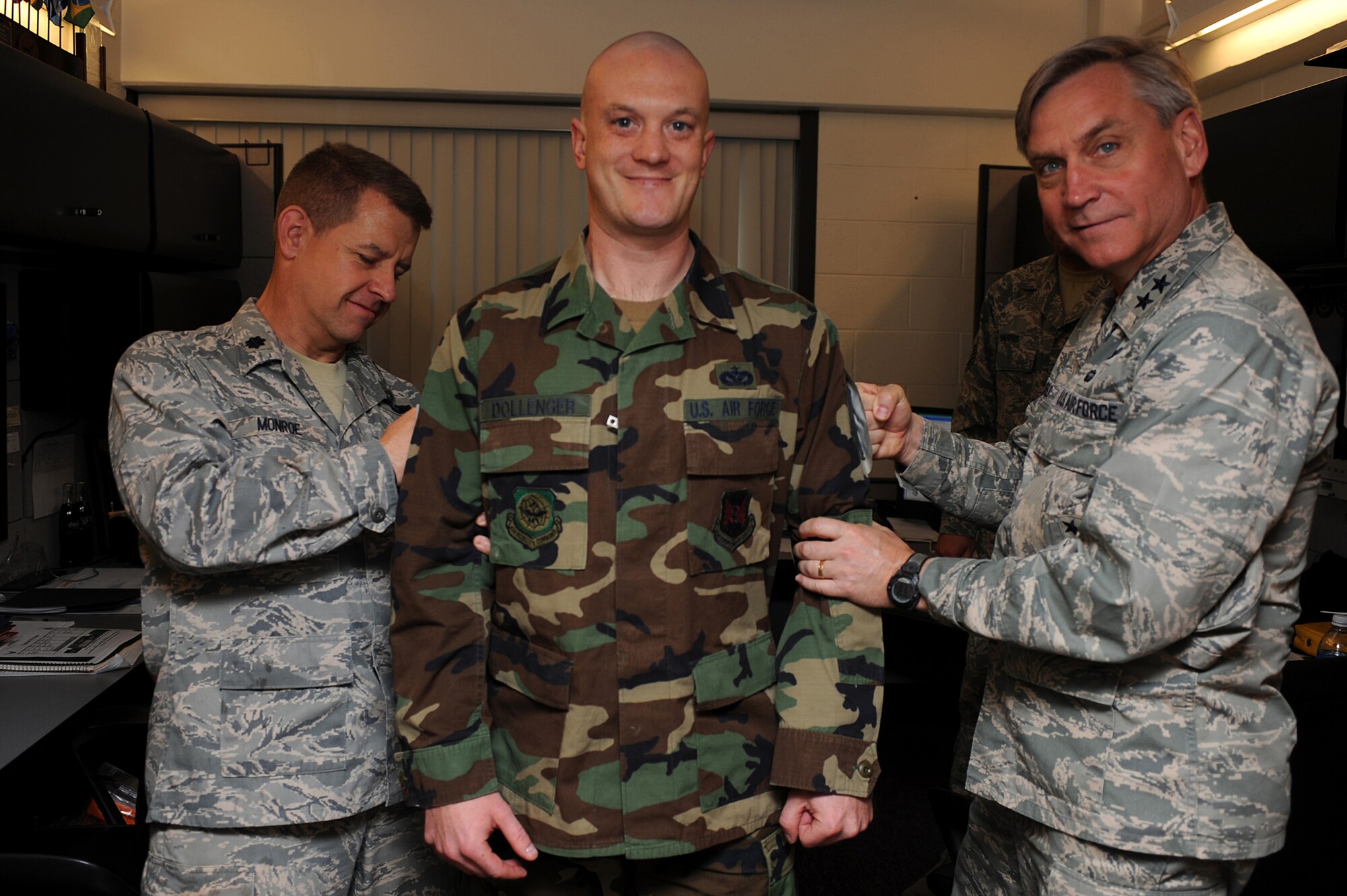 Major Gen. Kip Self, U.S. Air Force Expeditionary Center commander, and Lt. Col. Mitchell Monroe, 421st Combat Training Squadron commander, tack master sergeant stripes on Tech Sgt. George Dollenger, also with the 421st CTS, on May 14 at the center.  Ten Airmen from the Expeditionary Center were selected for E-7 stripes. (U.S. Air Force Photo/Staff Sgt. Nathan G. Bevier) 