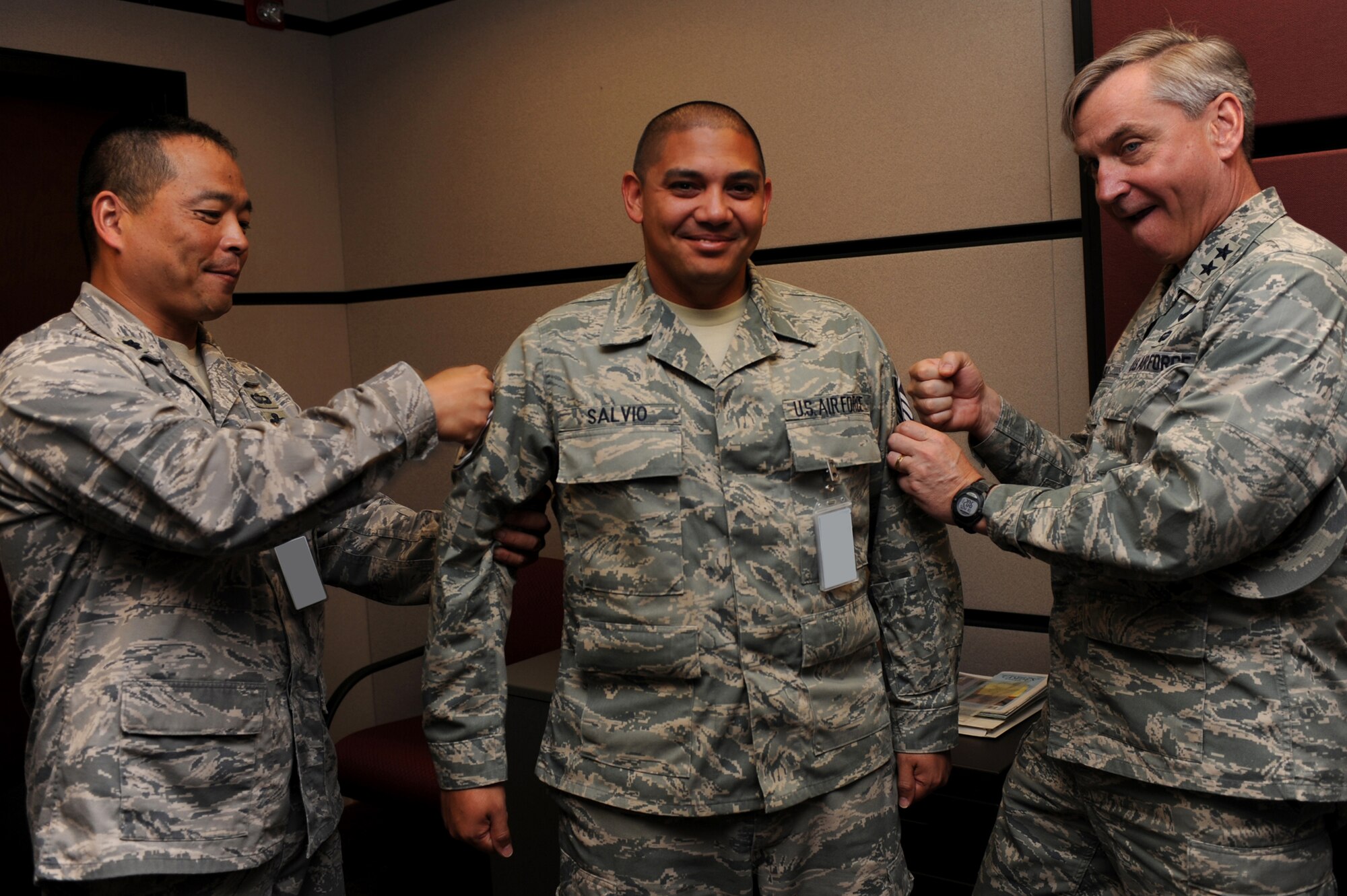 Major Gen. Kip Self, U.S. Air Force Expeditionary Center commander, and Lt. Col. Steve Sugiyama, Expeditionary Operations School deputy commandant, tack master sergeant stripes on Tech Sgt. Don Salvio, also with the EOS, on May 14 at the center.  Ten Airmen from the Expeditionary Center were selected for E-7 stripes. (U.S. Air Force Photo/Staff Sgt. Nathan G. Bevier) 