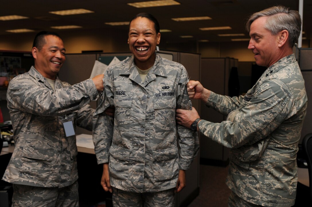 Major Gen. Kip Self, U.S. Air Force Expeditionary Center commander, and Lt. Col. Steve Sugiyama, Expeditionary Operations School deputy commandant, tack master sergeant stripes on Tech Sgt. Latrice Reese, also with the EOS, on May 14 at the center.  Ten Airmen from the Expeditionary Center were selected for E-7 stripes. (U.S. Air Force Photo/Staff Sgt. Nathan G. Bevier) 