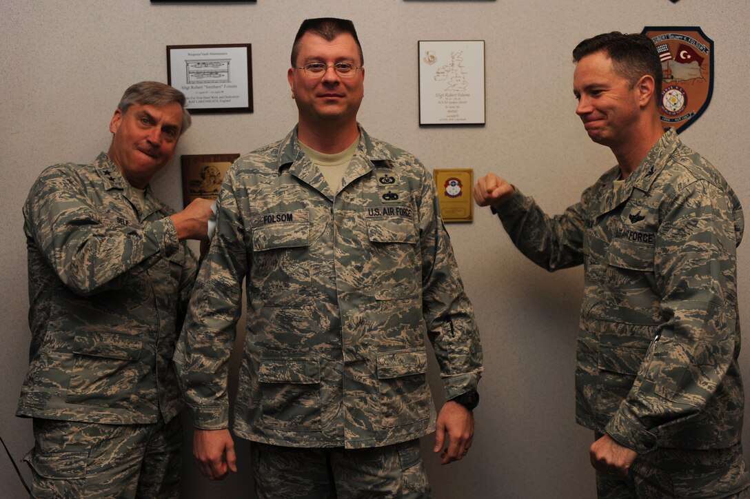 Major Gen. Kip Self, U.S. Air Force Expeditionary Center commander, and Col. Mark Loeben, Expeditionary Center acting vice commander, tack master sergeant stripes on Tech Sgt. Robert Folsom, Expeditionary Center NCO in charge of safety, on May 14 at the center.  Ten Airmen from the Expeditionary Center were selected for E-7 stripes. (U.S. Air Force Photo/Staff Sgt. Nathan G. Bevier) 