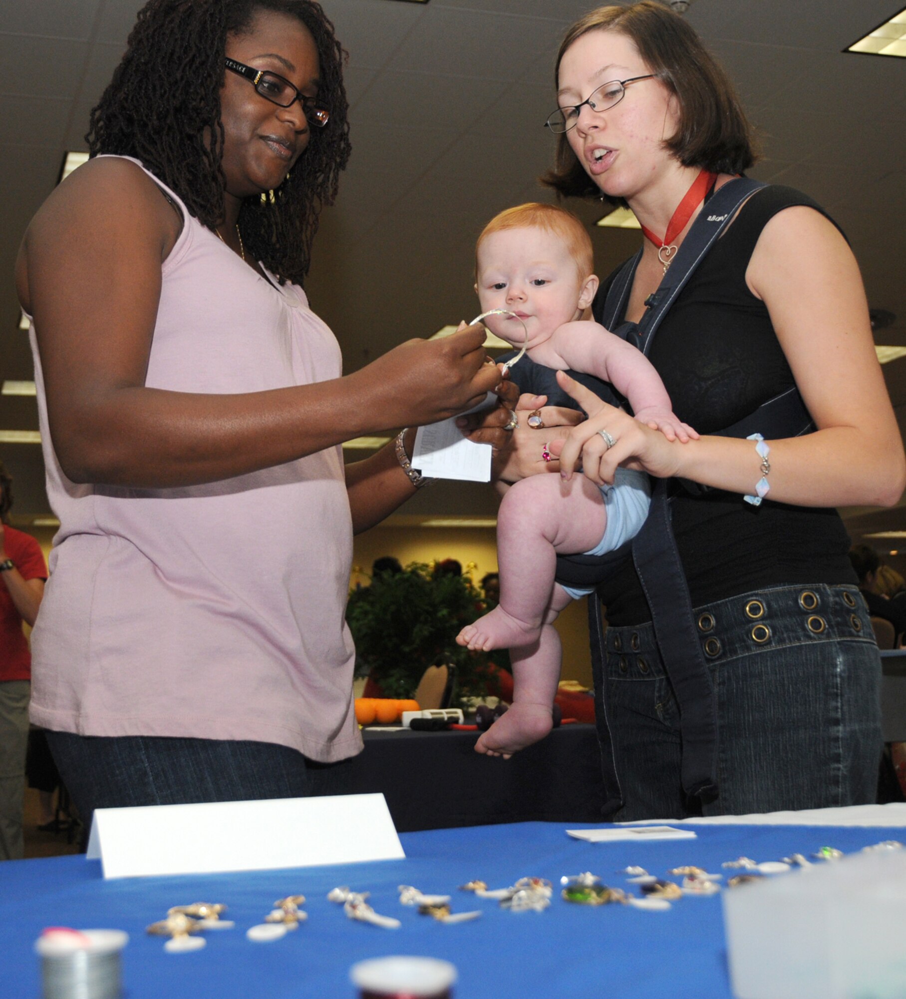 Rachel Jones admires jewelry made by Aubrey Bouck, owner of Brandavir Jewelry.  Mrs. Bouck, wife of Airman 1st Class Andrew Bouck, 81st Medical Support Squadron, holds their 6½-month old son, Alex.  Mrs. Jones is married to Tech. Sgt. Gregory Jones, 81st Medical Operations Squadron.  (U.S. Air Force photo by Kemberly Groue)