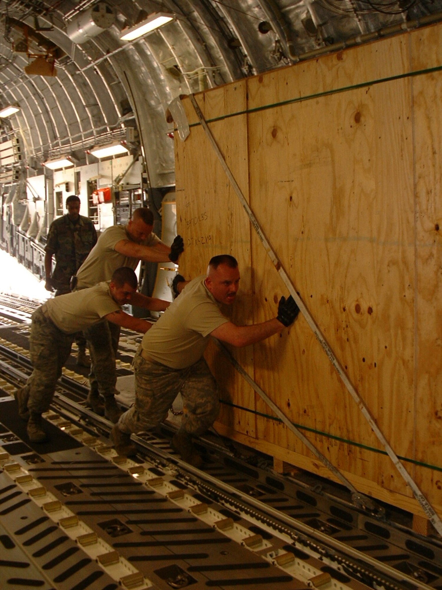 Senior Airman Glyn Meranto, Airman Travis Freeman and Staff Sgt. David House, from back, push a heavy T-2 Pallet train into position on an Australian C-17 Aircraft for the loadmaster to secure into place. (Courtesy photo)