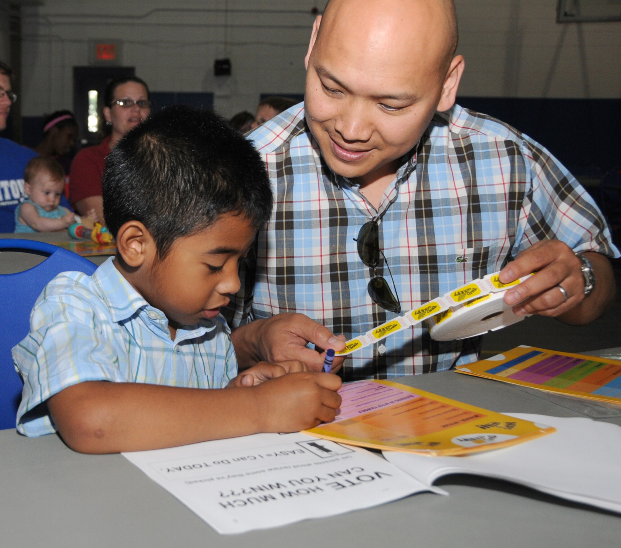 Five-year-old Jonah Canlas and his dad, Lt. Col. Jimmy Canlas, 45th Airlift Squadron commander, play “That’s the Ticket” Saturday at the youth center.  Jonah’s mother, Joy, and his sister Malea, 4, also participated at the program sponsored by family advocacy.  The program, presented by Kevin McMahon, is intended to help parents bring solid order and structure to family life, while inspiring children to set new goals, master positive habits and earn the things they want.  (U.S. Air Force photo by Kemberly Groue)