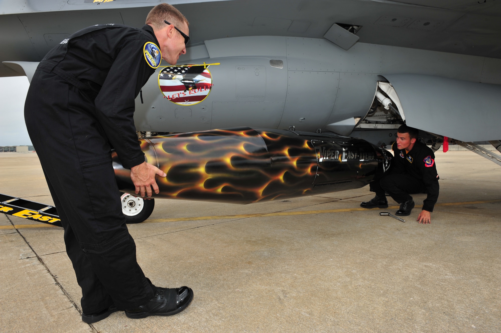 SHAW AIR FORCE BASE, S.C.- Senior Airman Anthony J. Modugno, left, and Staff Sergeant James A. Griggs, both dedicated crew chiefs of the Viper East F-16 Demonstration Team place a travel pod into position so it can be hung on the F-16 aircraft. The pair volunteered their personal time refinishing the pod over a two week period to bring it up to show standards, 14 May 2009. (U.S. Air Force Photo by: TSgt Josef Cole)
 
