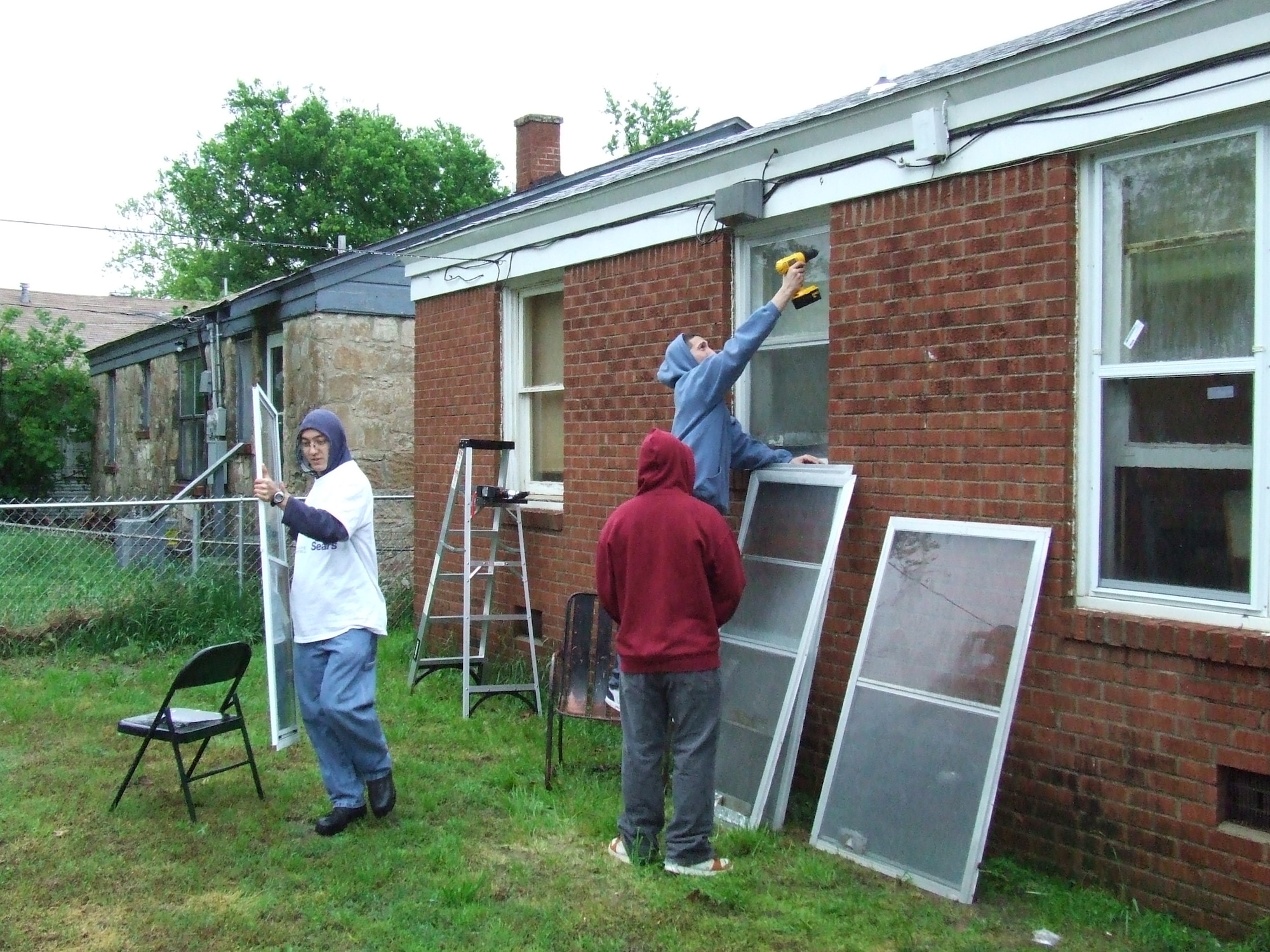 Members of the 552nd Air Control Networks Squadron install new storm windows on the Lamberts' home as part of the Rebuilding Together community service project. (US Air Force Photo courtesy of Airman First Class Taj V. Preciado)