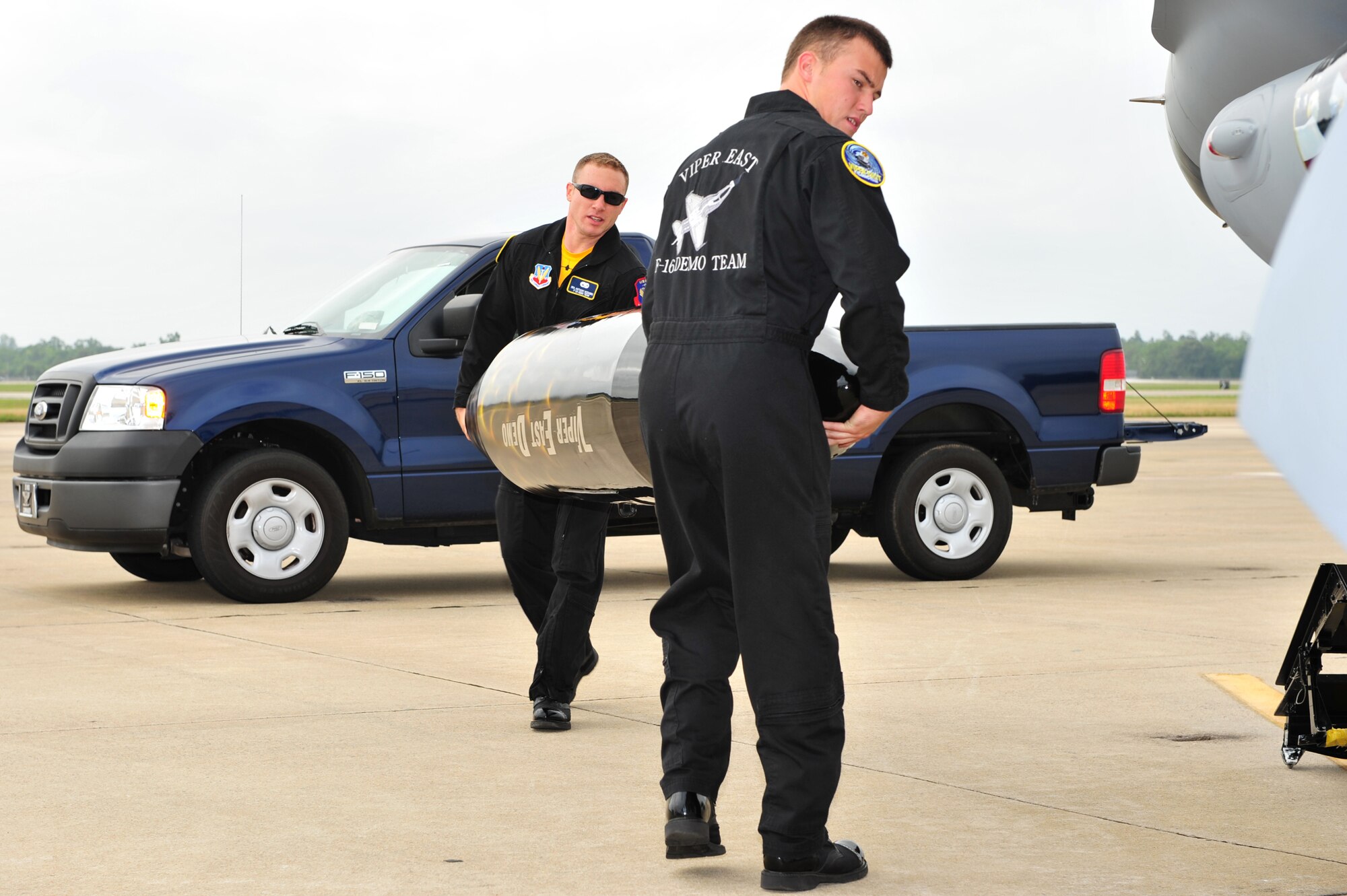 SHAW AIR FORCE BASE, S.C.- Senior Airman Anthony J. Modugno, background, and Staff Sergeant James A. Griggs, both dedicated crew chiefs of the Viper East F-16 Demonstration Team carry a travel pod into position so it can be hung on the F-16 aircraft. The pair volunteered their personal time refinishing the pod over a two week period to bring it up to show standards, 14 May 2009. (U.S. Air Force Photo by: TSgt Josef Cole)
 
