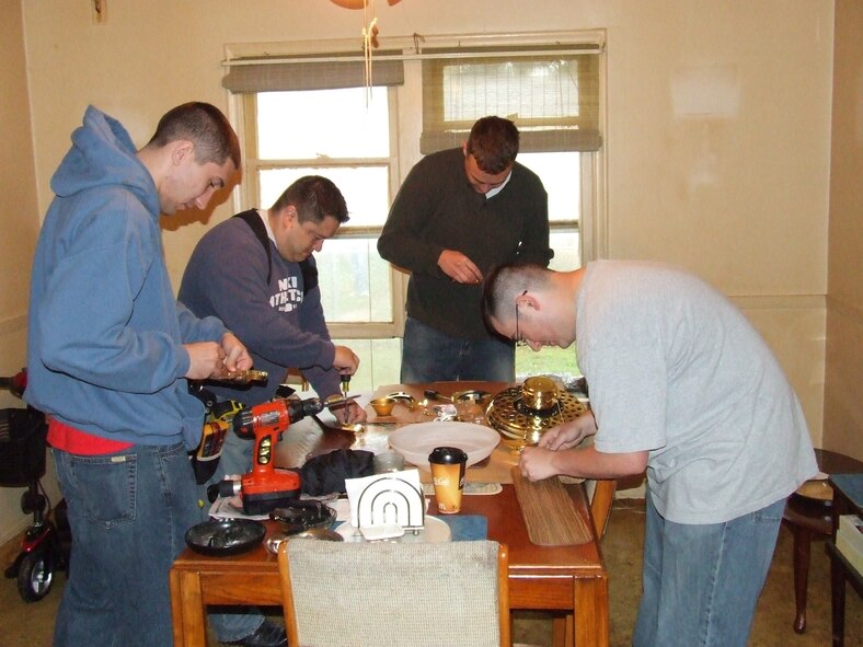 Members of the 552nd Air Control Networks Squadron assemble new ceiling fans for the Lamberts' home as part of the Rebuilding Together community service project. (US Air Force Photo courtesy of Airman First Class Taj V. Preciado)