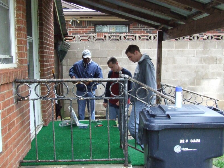 Lt. Col. Arthur Moore, commander, 552nd Air Control Networks Squadron, works with two of his Airmen to replace the outdoor carpet on the porch of the Lamberts' home. (US Air Force Photo courtesy of Airman First Class Taj V. Preciado)